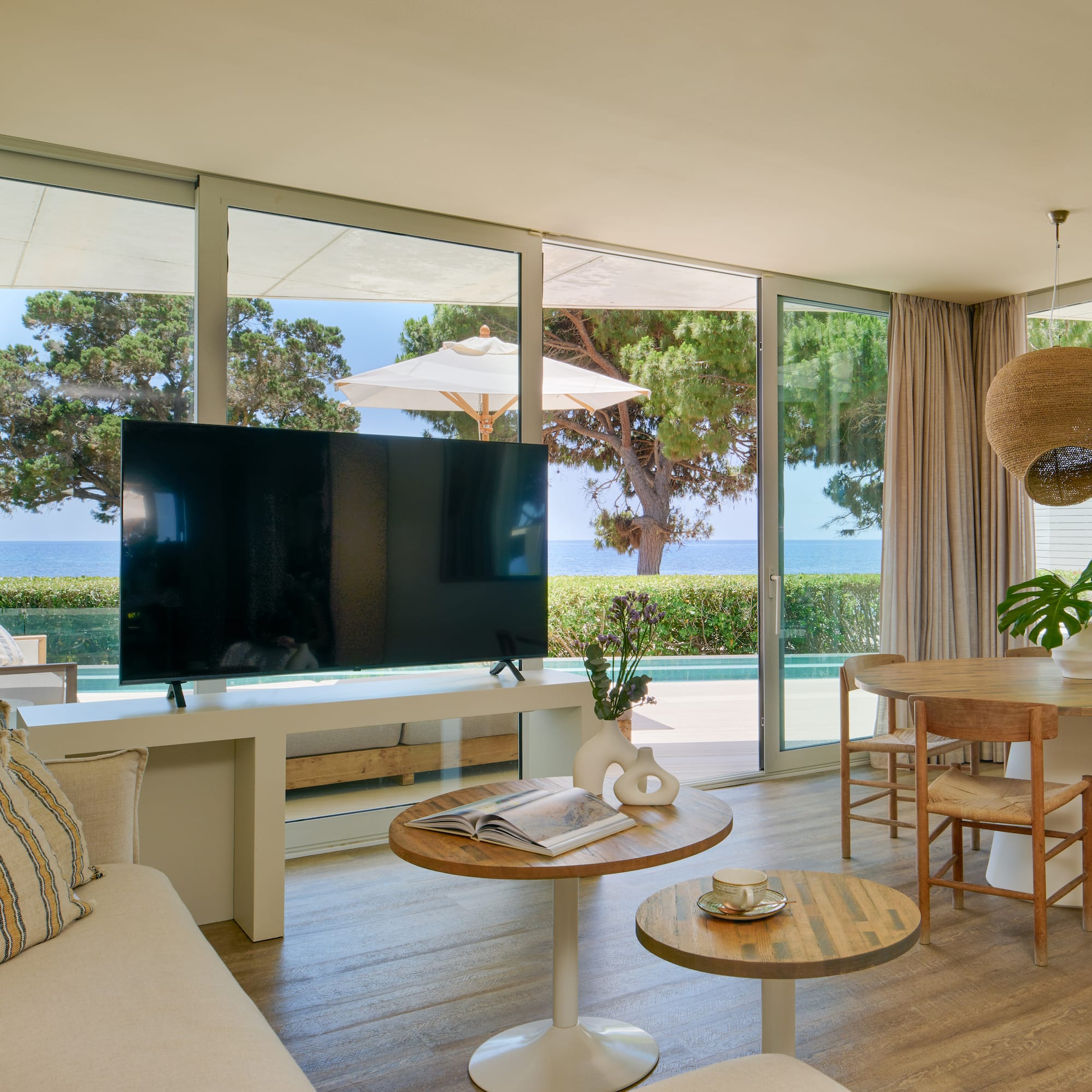 Luxury coastal living room with sea view, large TV, and dining area.