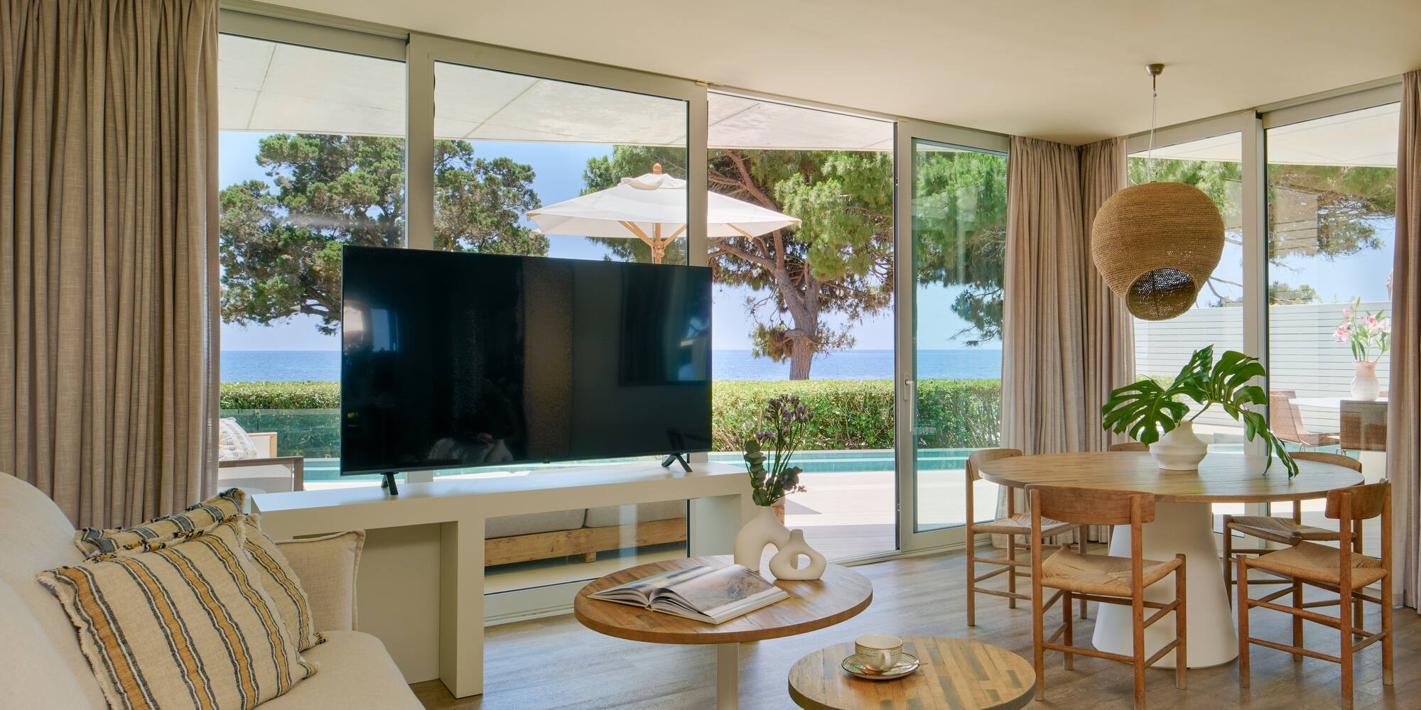 Luxury coastal living room with sea view, large TV, and dining area.