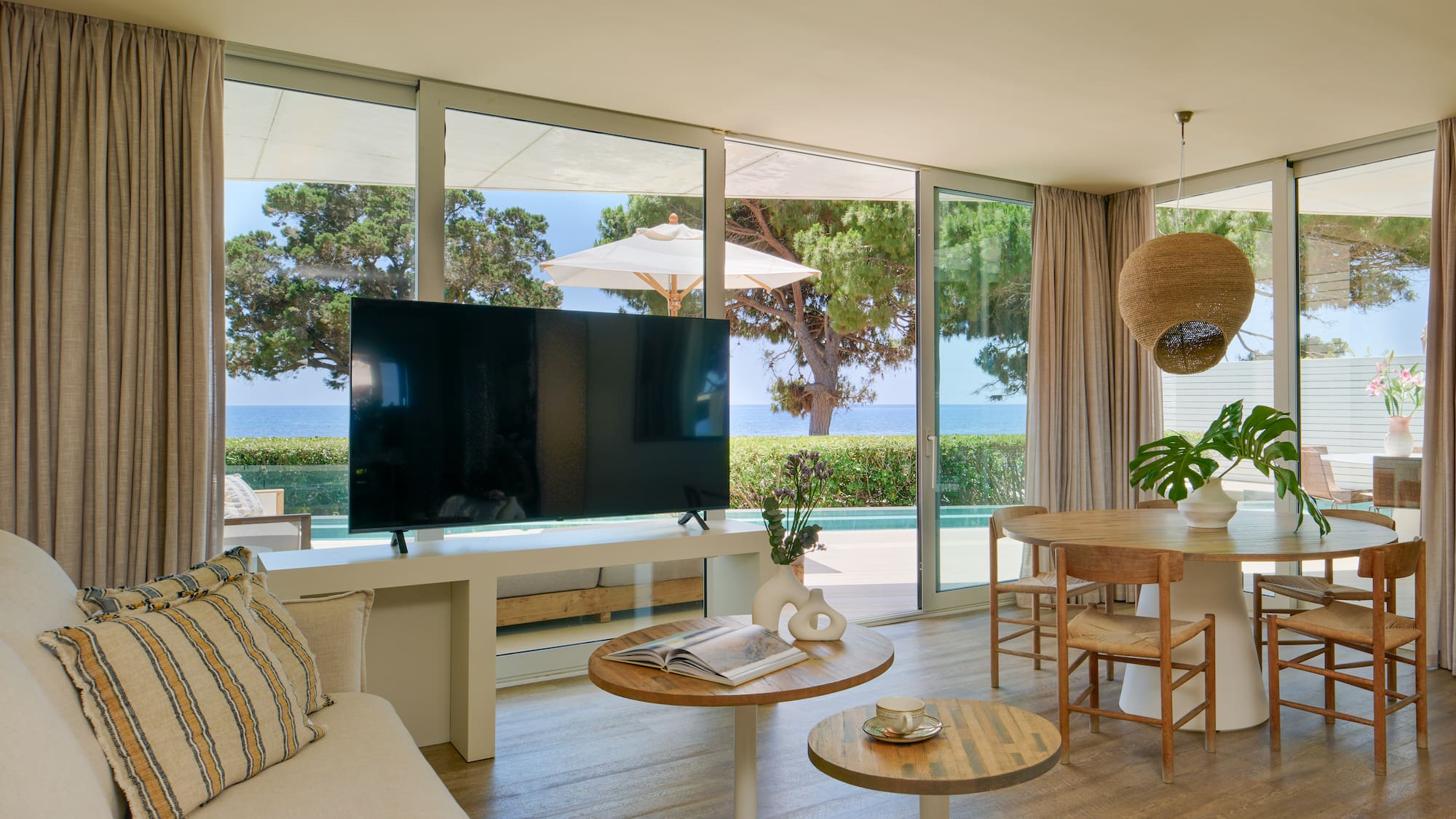 Luxury coastal living room with sea view, large TV, and dining area.