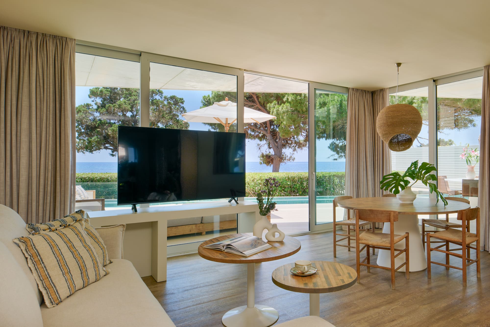 Luxury coastal living room with sea view, large TV, and dining area.