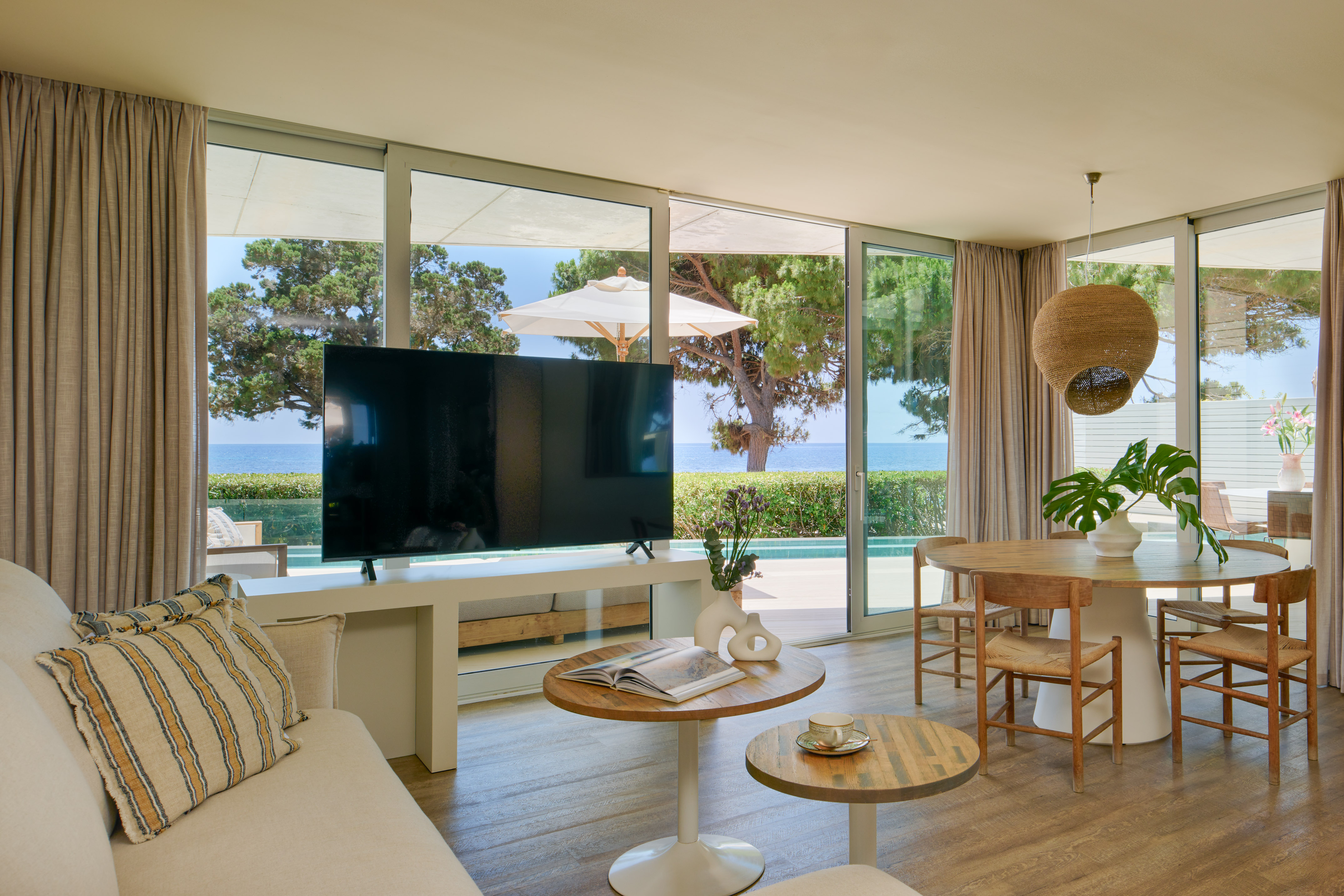 Luxury coastal living room with sea view, large TV, and dining area.