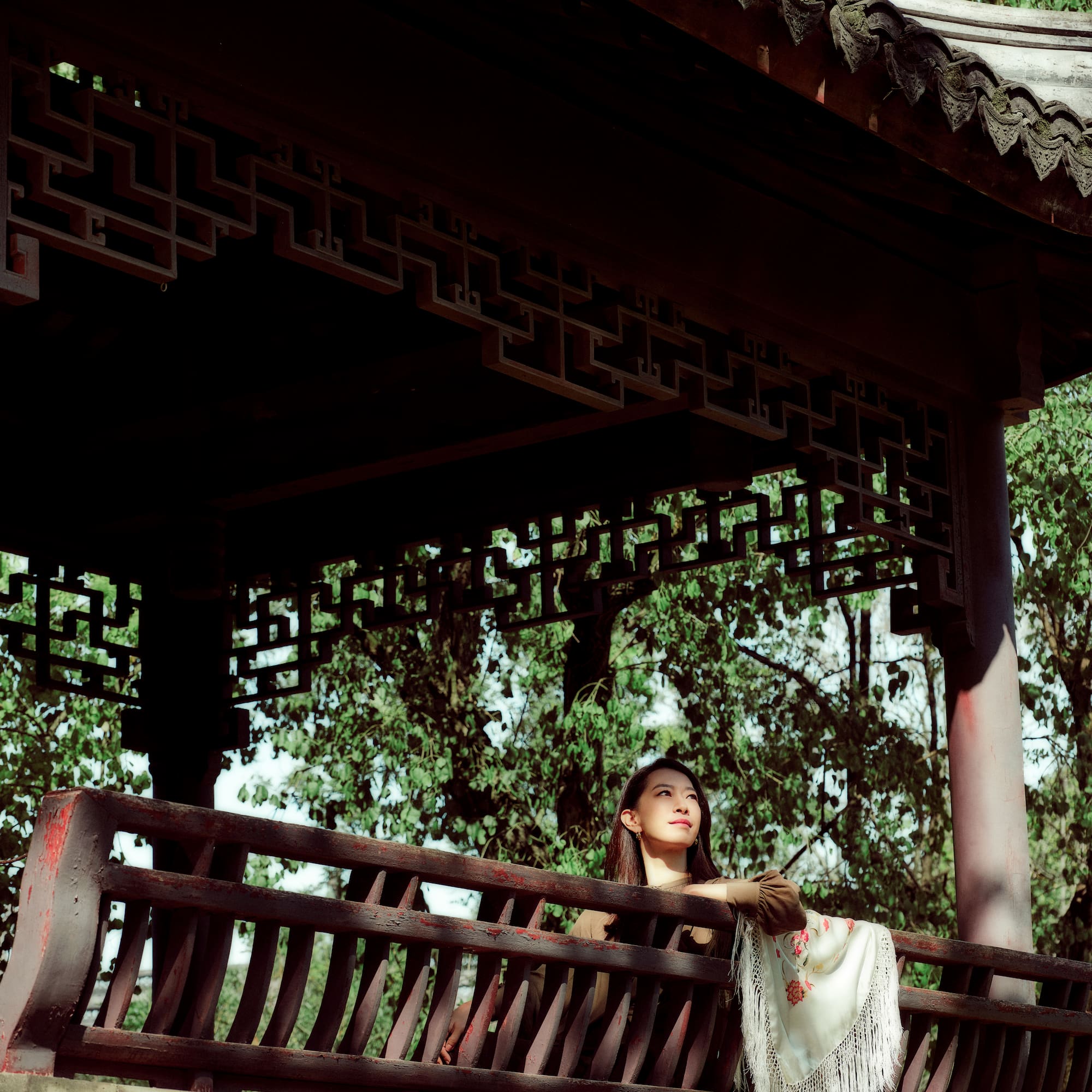 a woman sitting on a bench under a gazebo