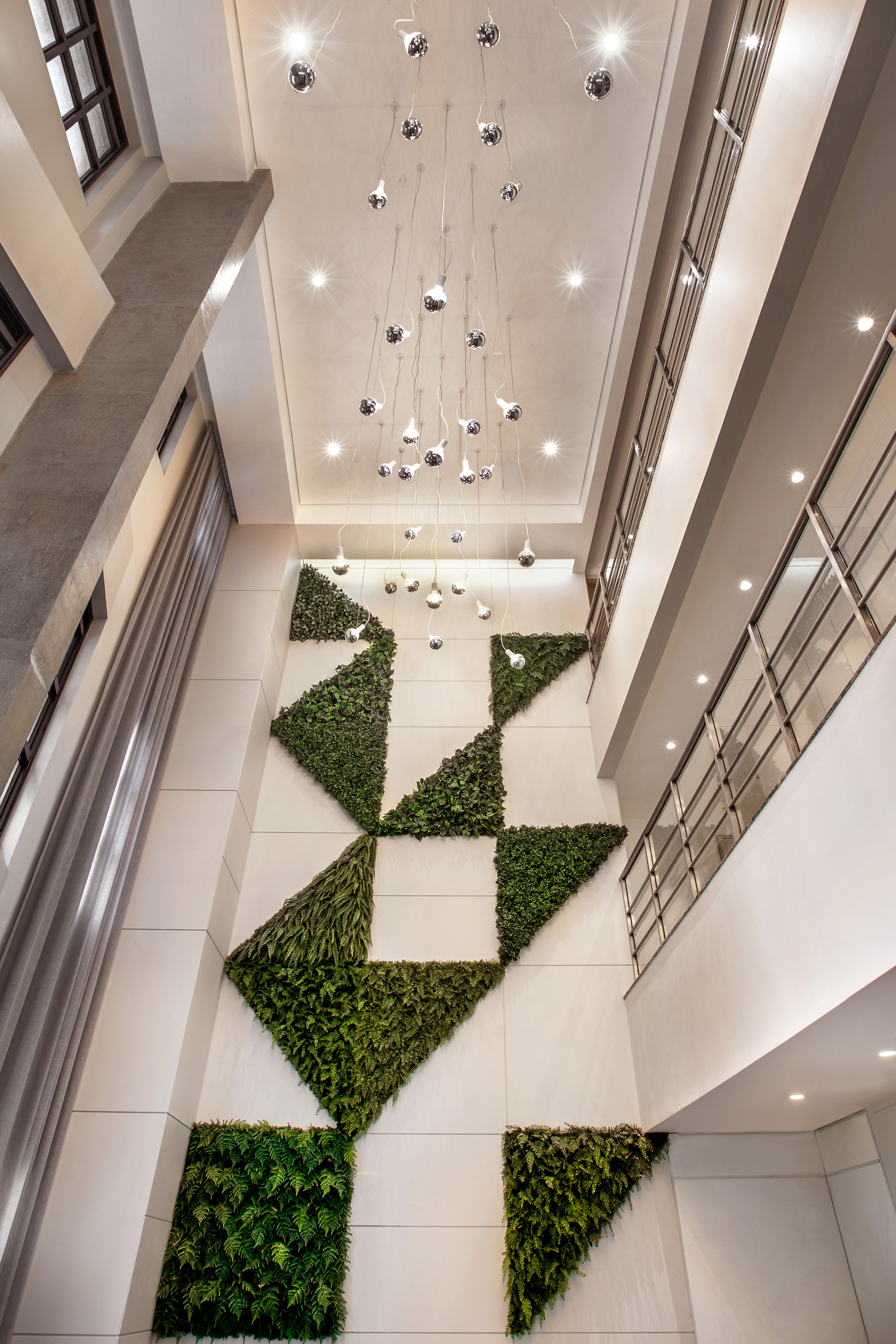 Lobby with geometric living wall, modern chandelier, and bright recessed lighting.
