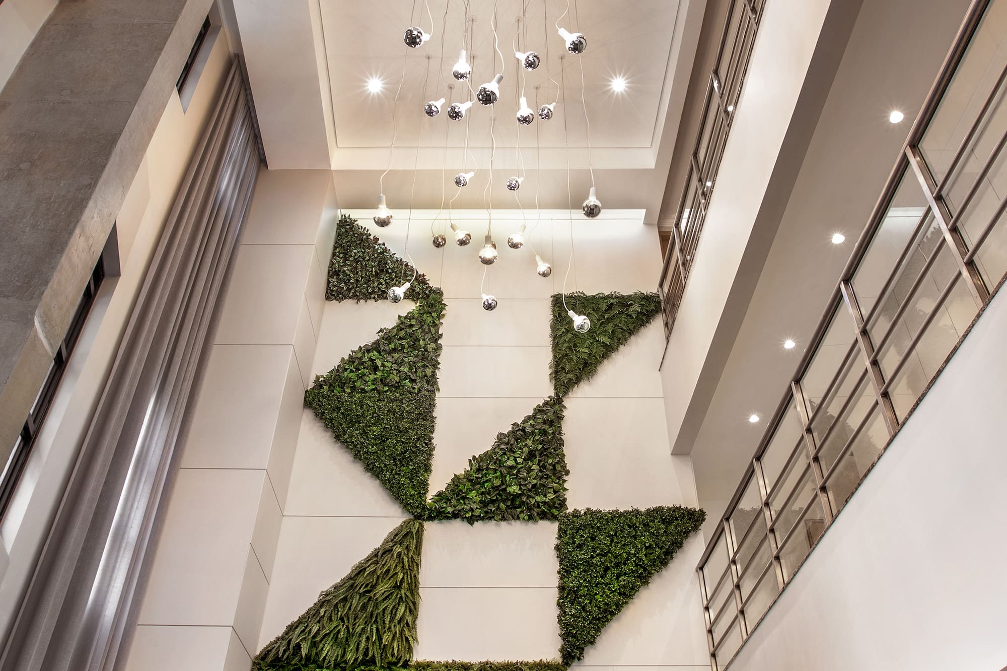 Lobby with geometric living wall, modern chandelier, and bright recessed lighting.