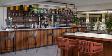 a bar with chairs and a shelf with bottles
