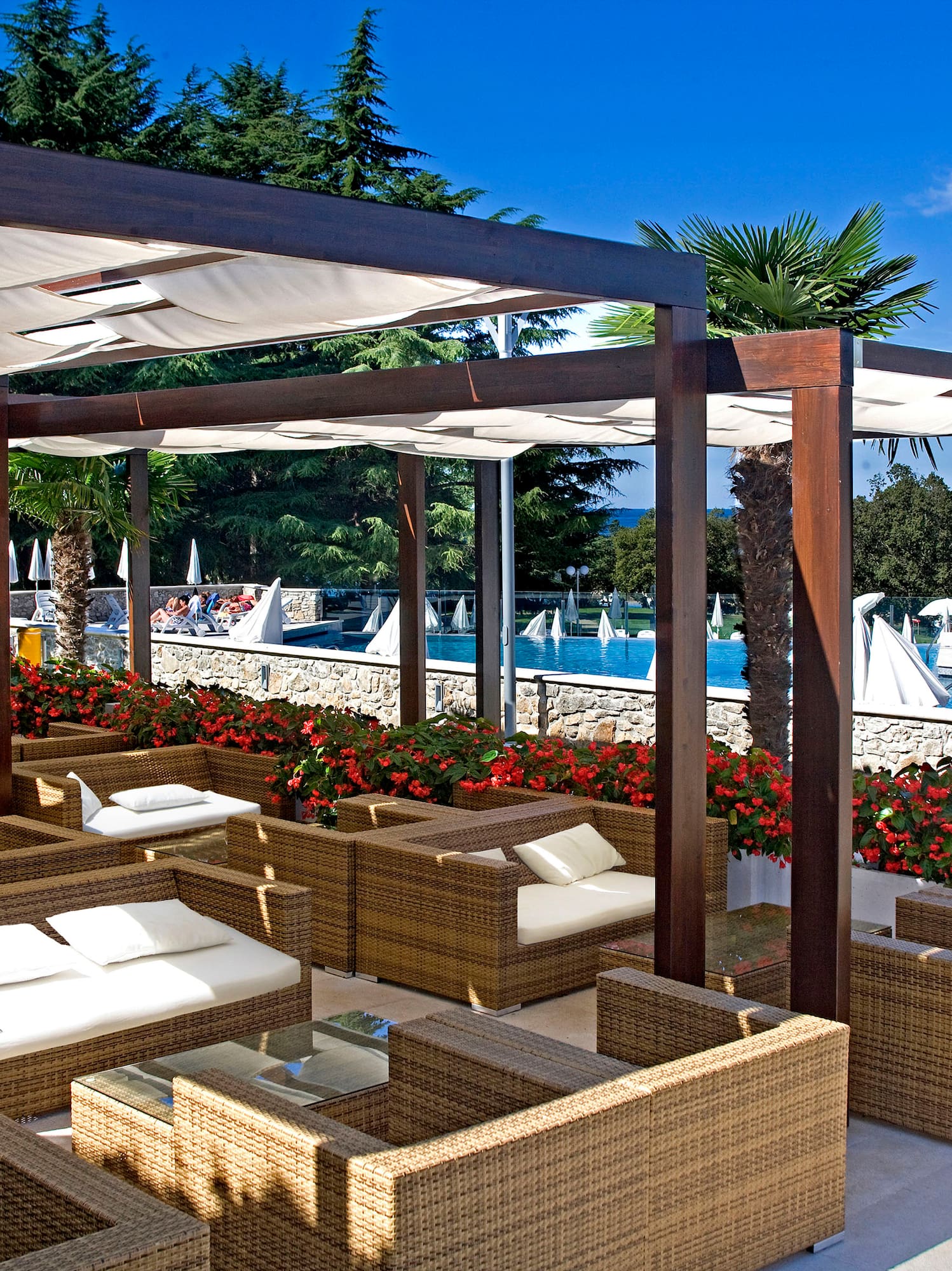 a patio with wicker furniture and a pool of water