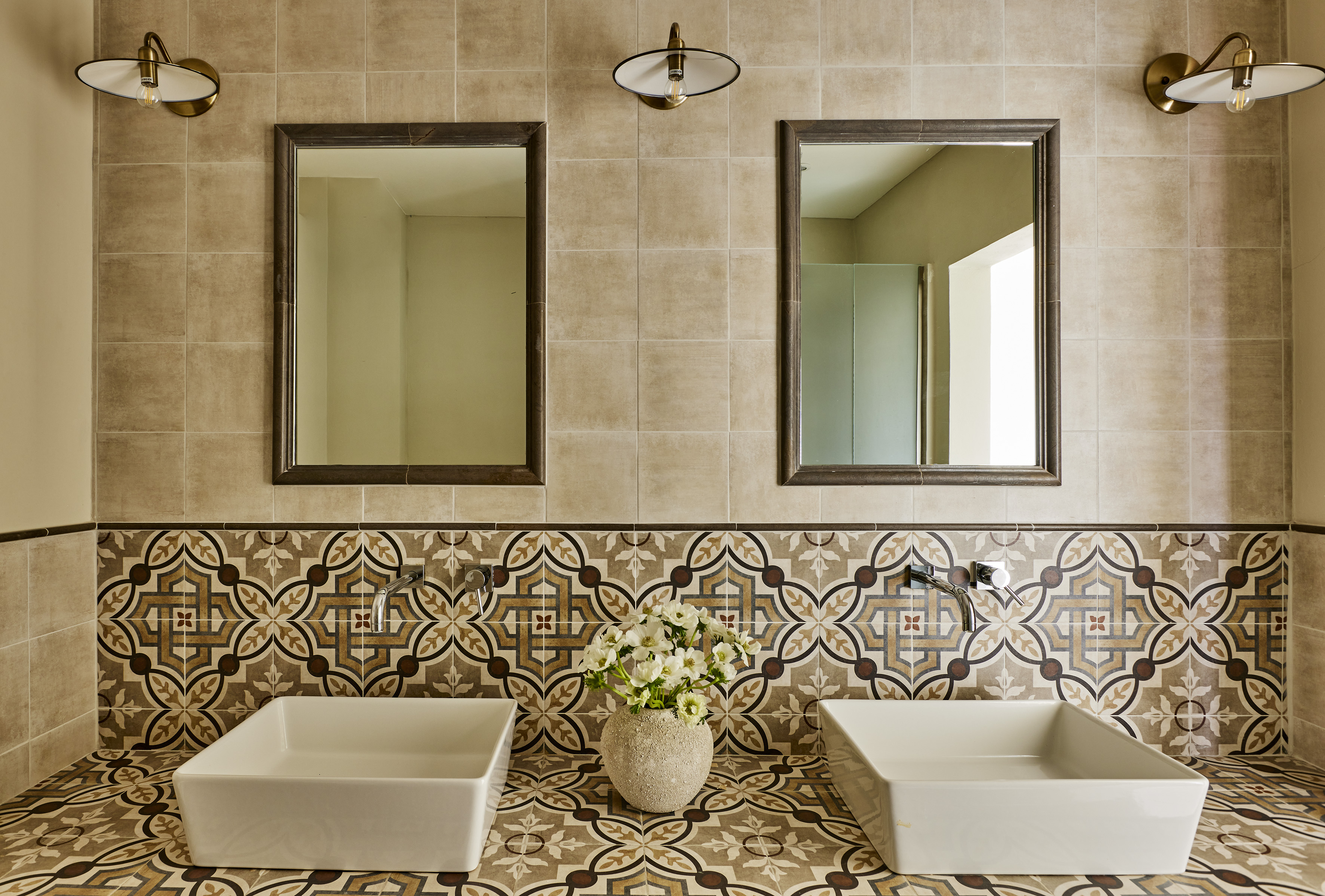 Mediterranean bathroom vanity with patterned tiles, dual sinks, and mirrors.