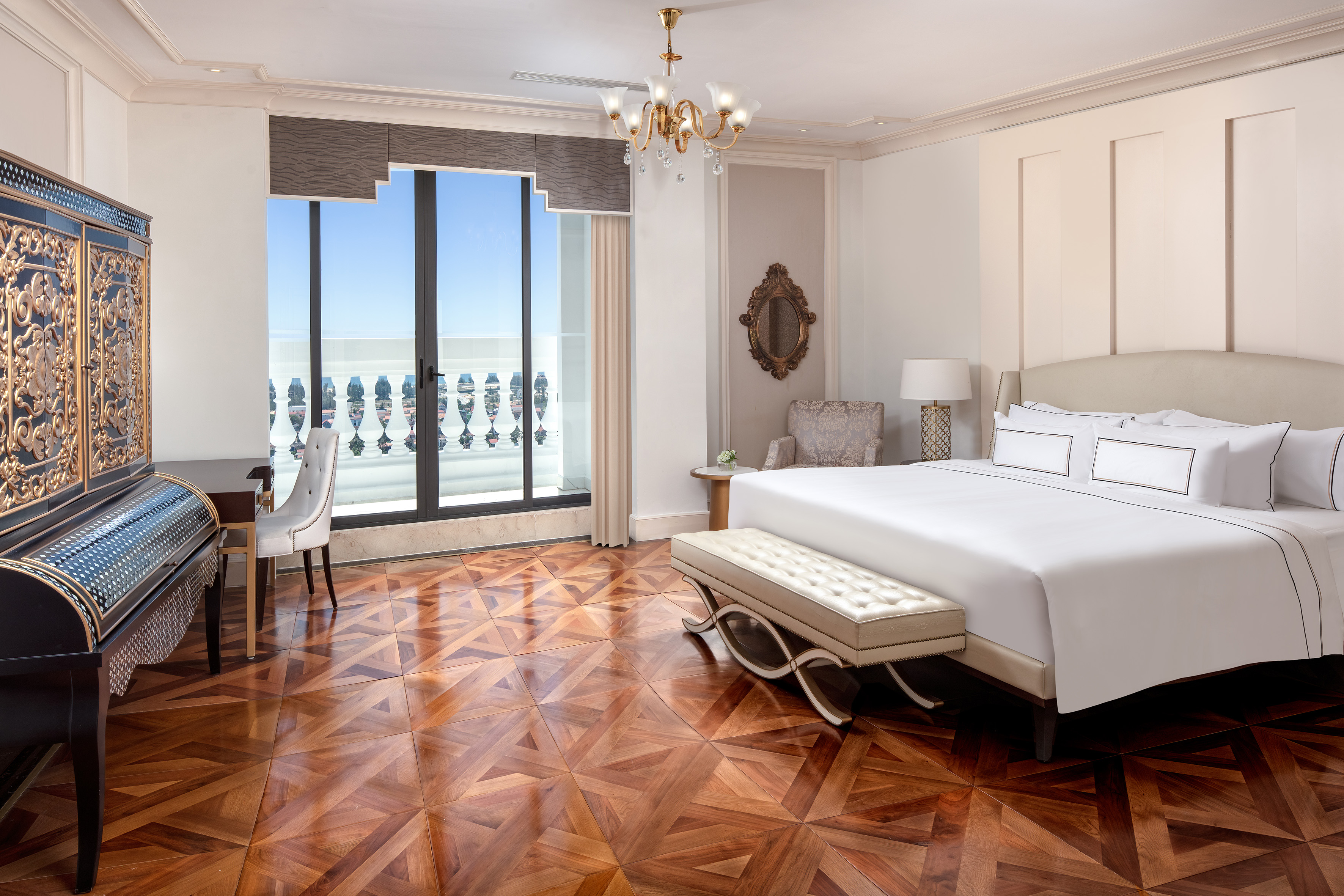 Luxury hotel bedroom with king bed, parquet floor, and balcony view.