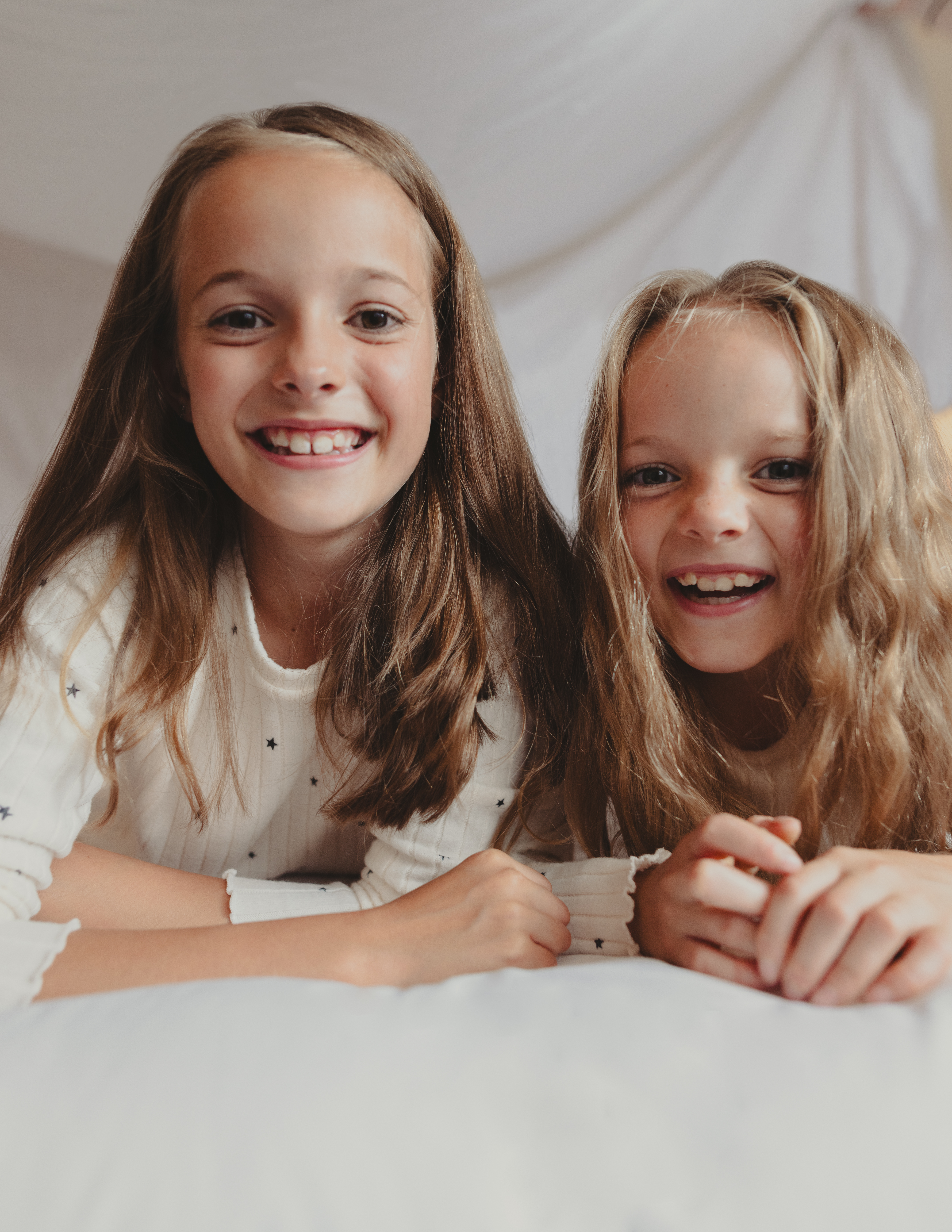 Happy young girls with long hair smiling at the camera.