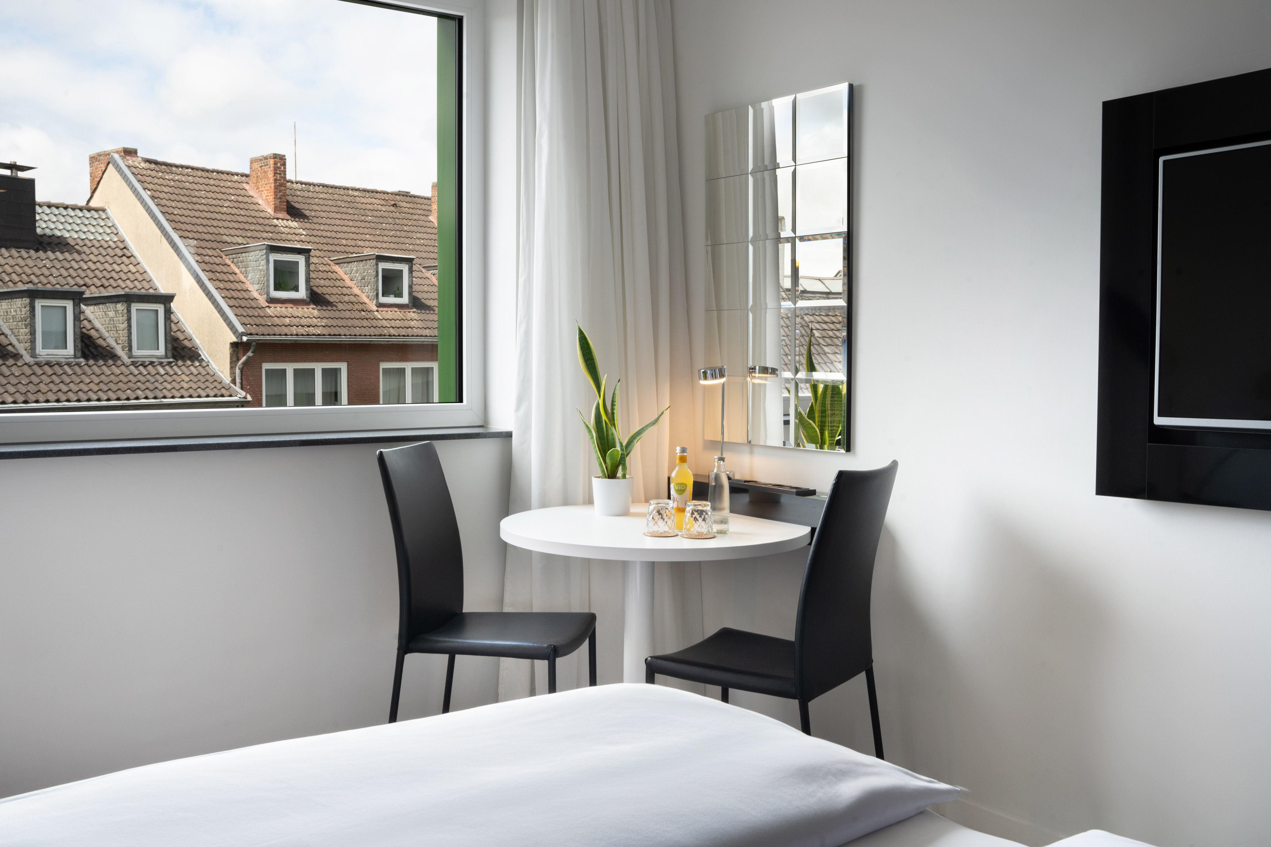 Cozy hotel room with round table, chairs, and window offering a city view.