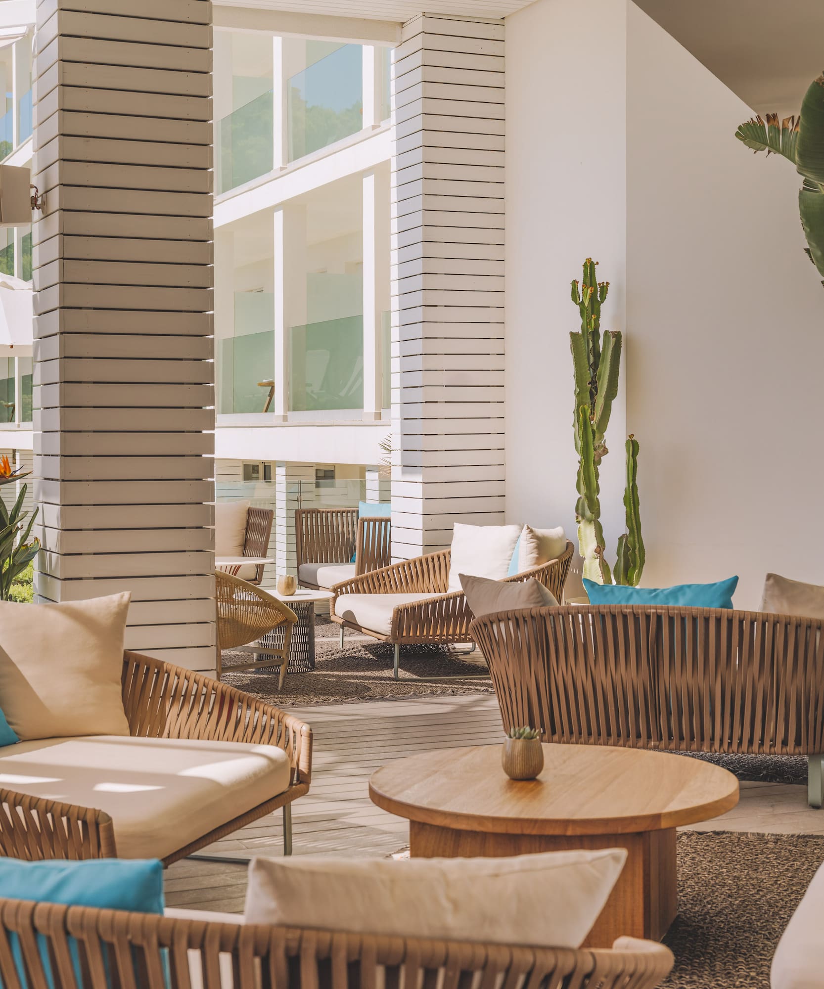 Modern resort outdoor lounge with rattan seating and bright turquoise pillows.