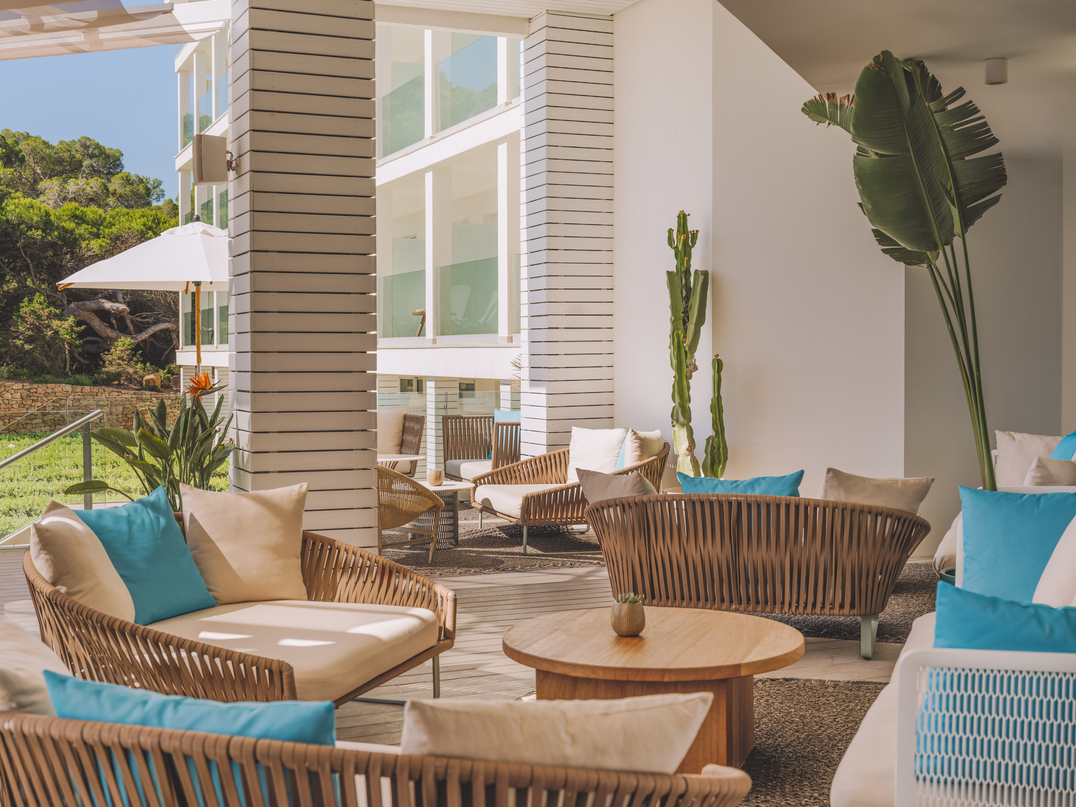Modern resort outdoor lounge with rattan seating and bright turquoise pillows.