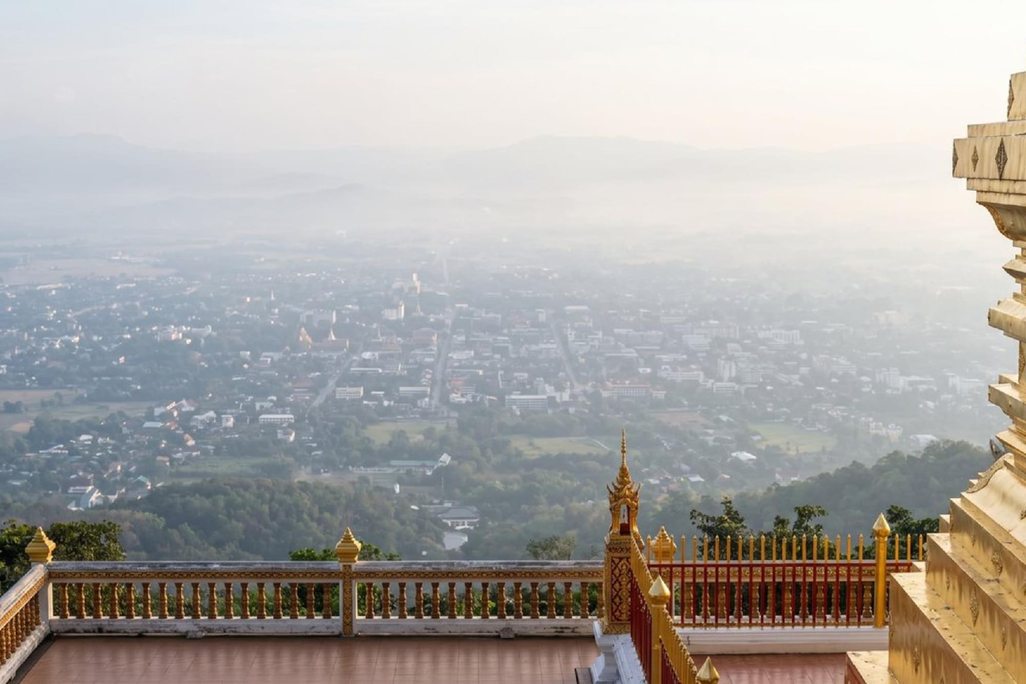 Golden temple view over hazy city and distant mountains.