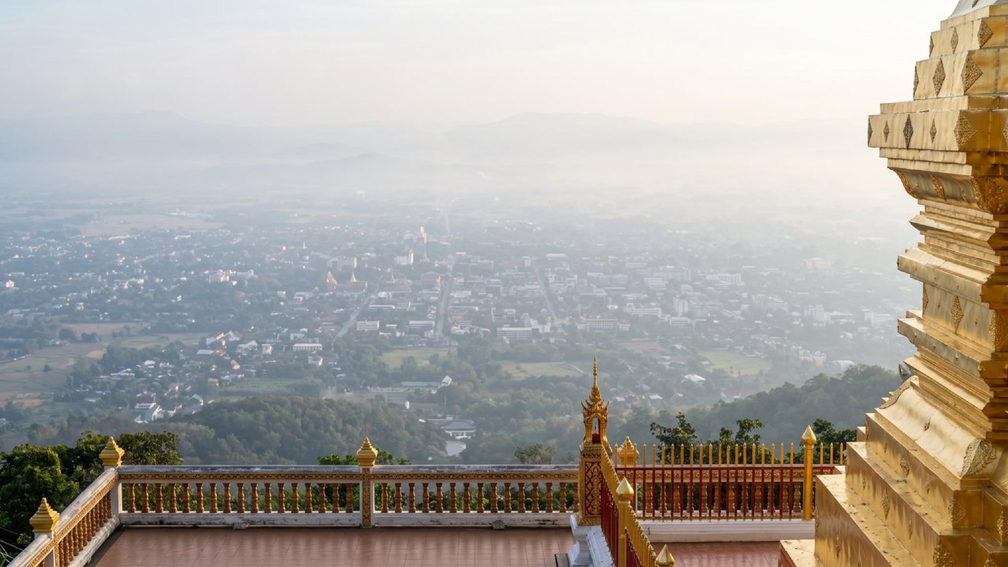 Golden temple view over hazy city and distant mountains.