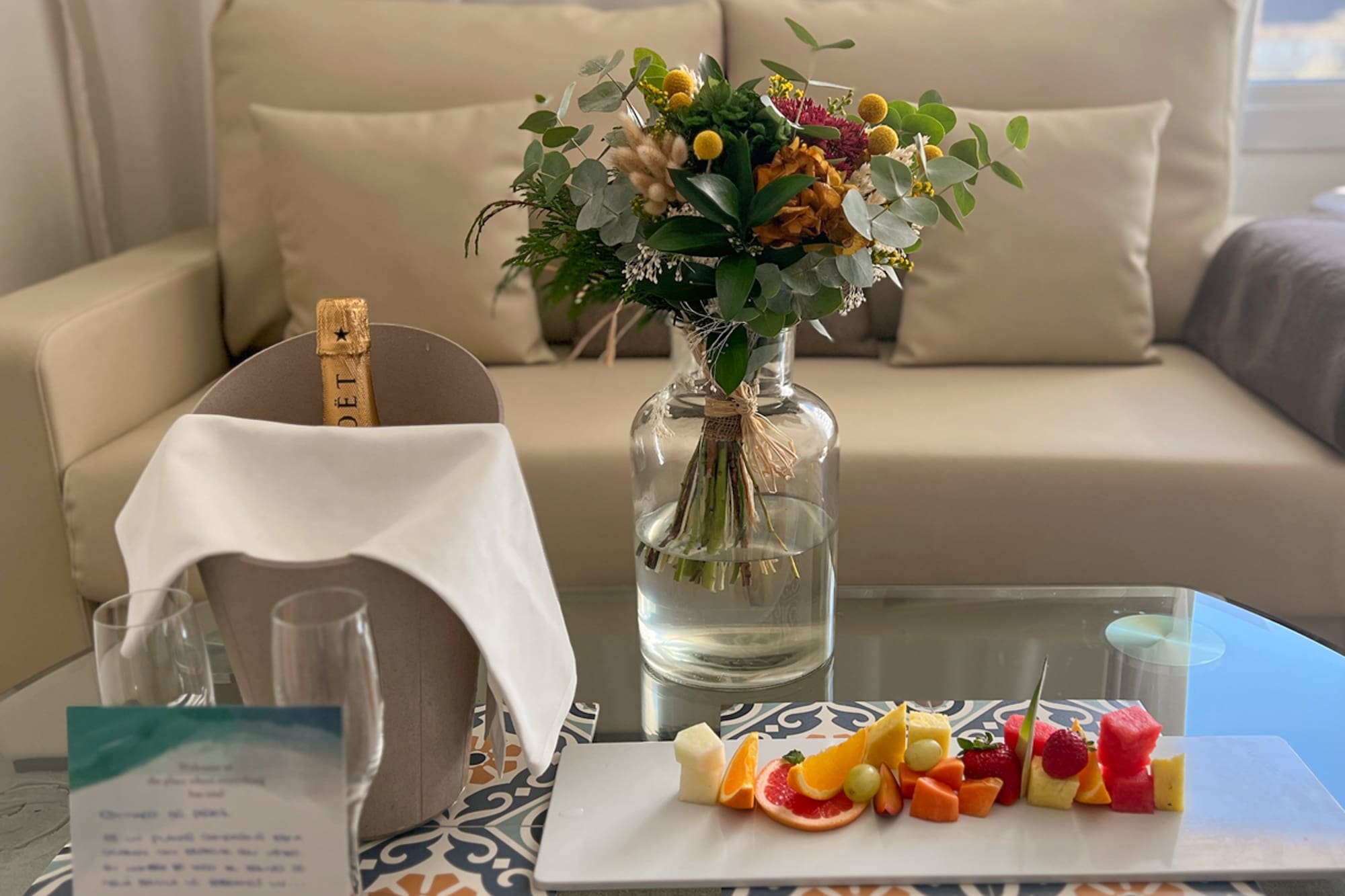 Champán, flores y fruta en mesa de cristal, detalle de bienvenida Meliá.