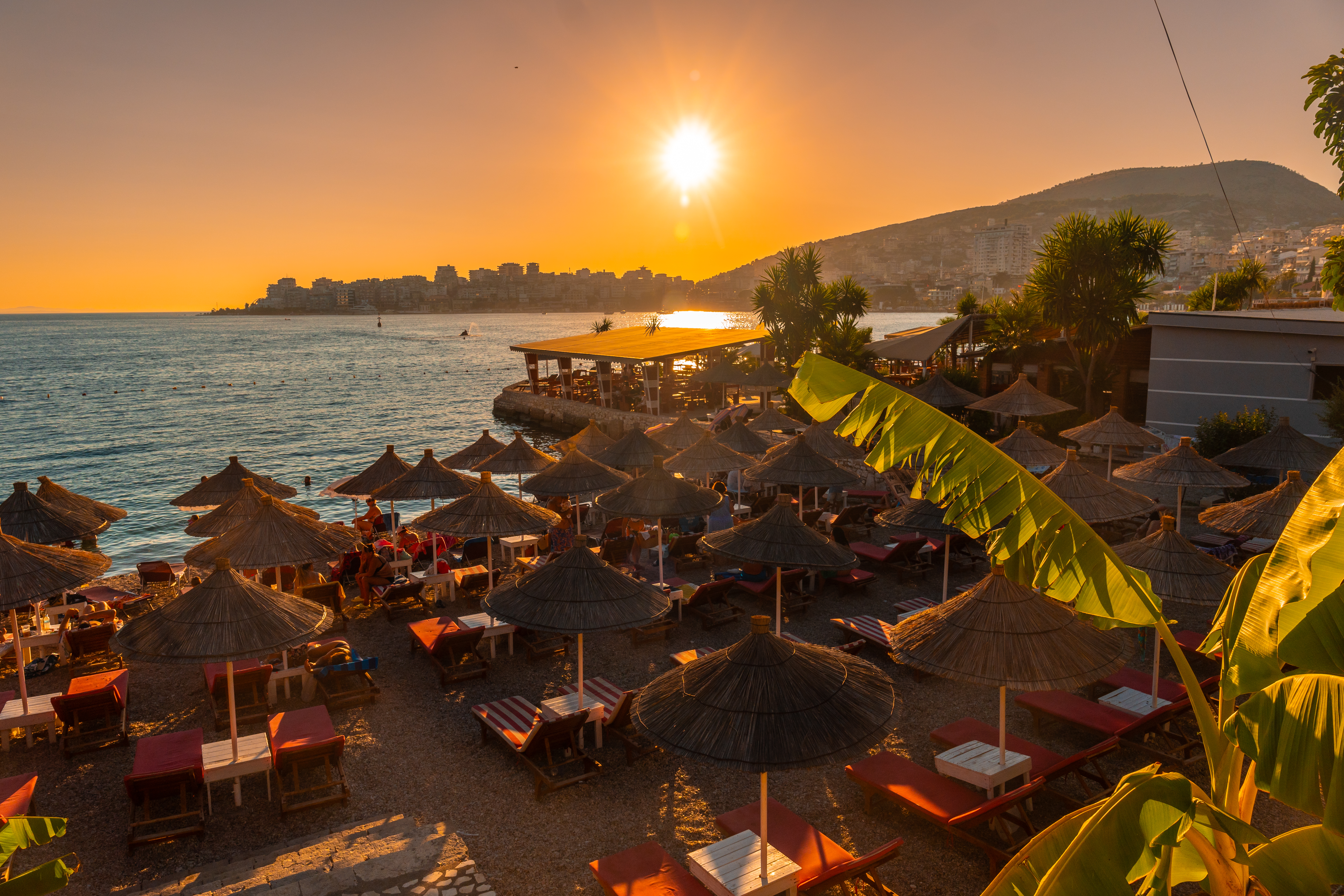 a beach with umbrellas and chairs and a beach in the background