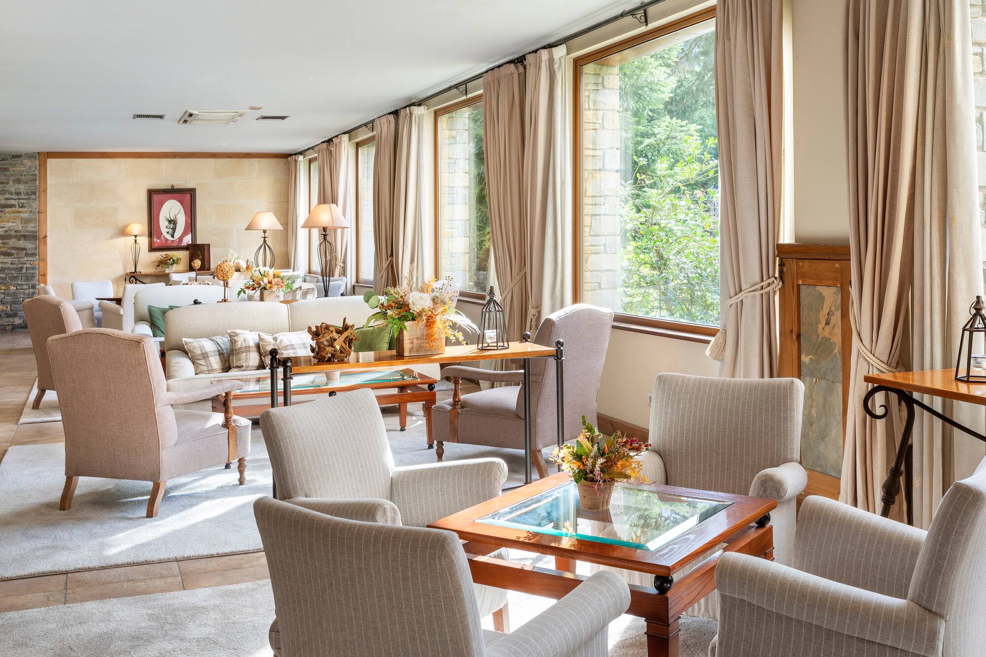Comfortable hotel lounge with large windows, soft seating, and stone walls.