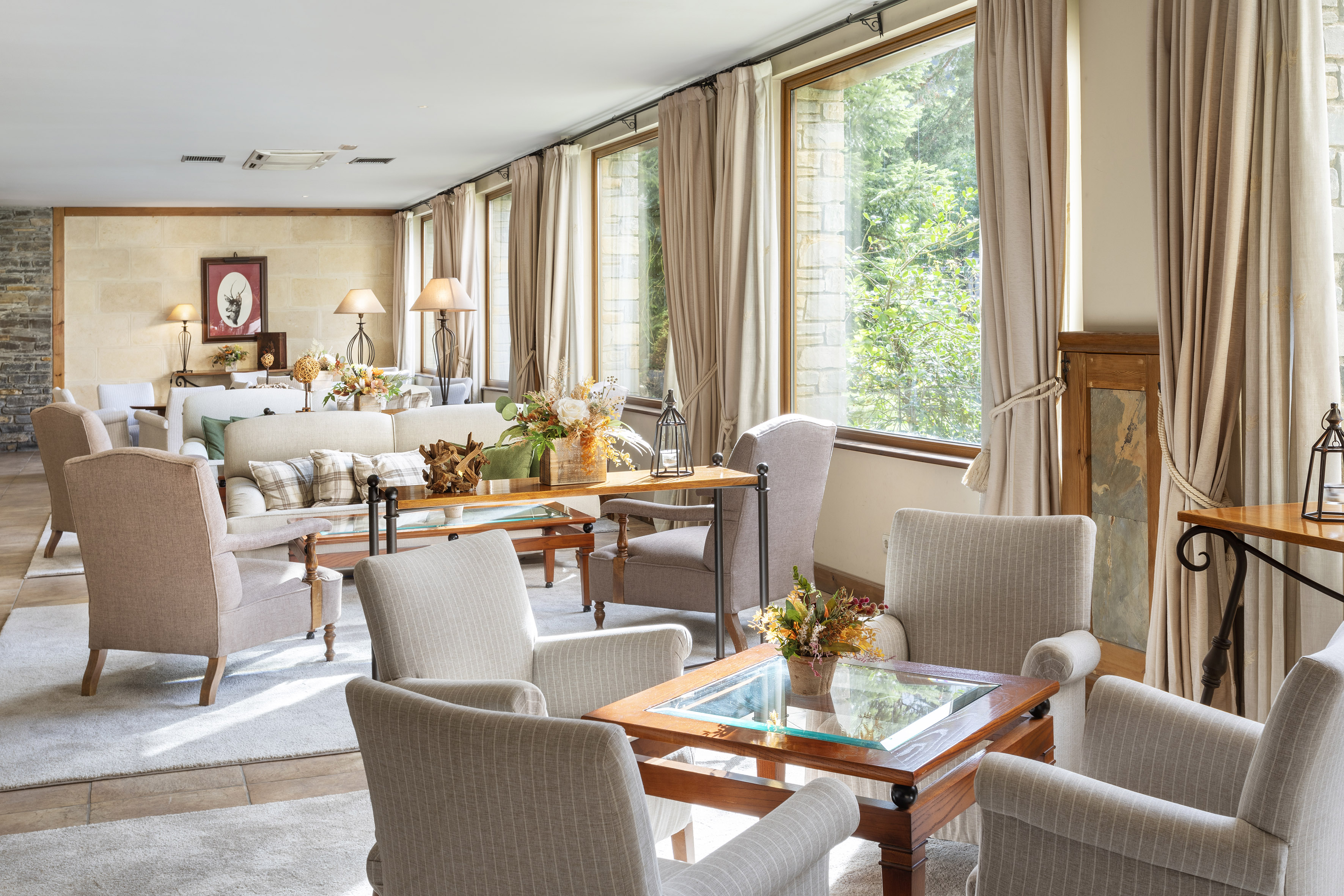Comfortable hotel lounge with large windows, soft seating, and stone walls.
