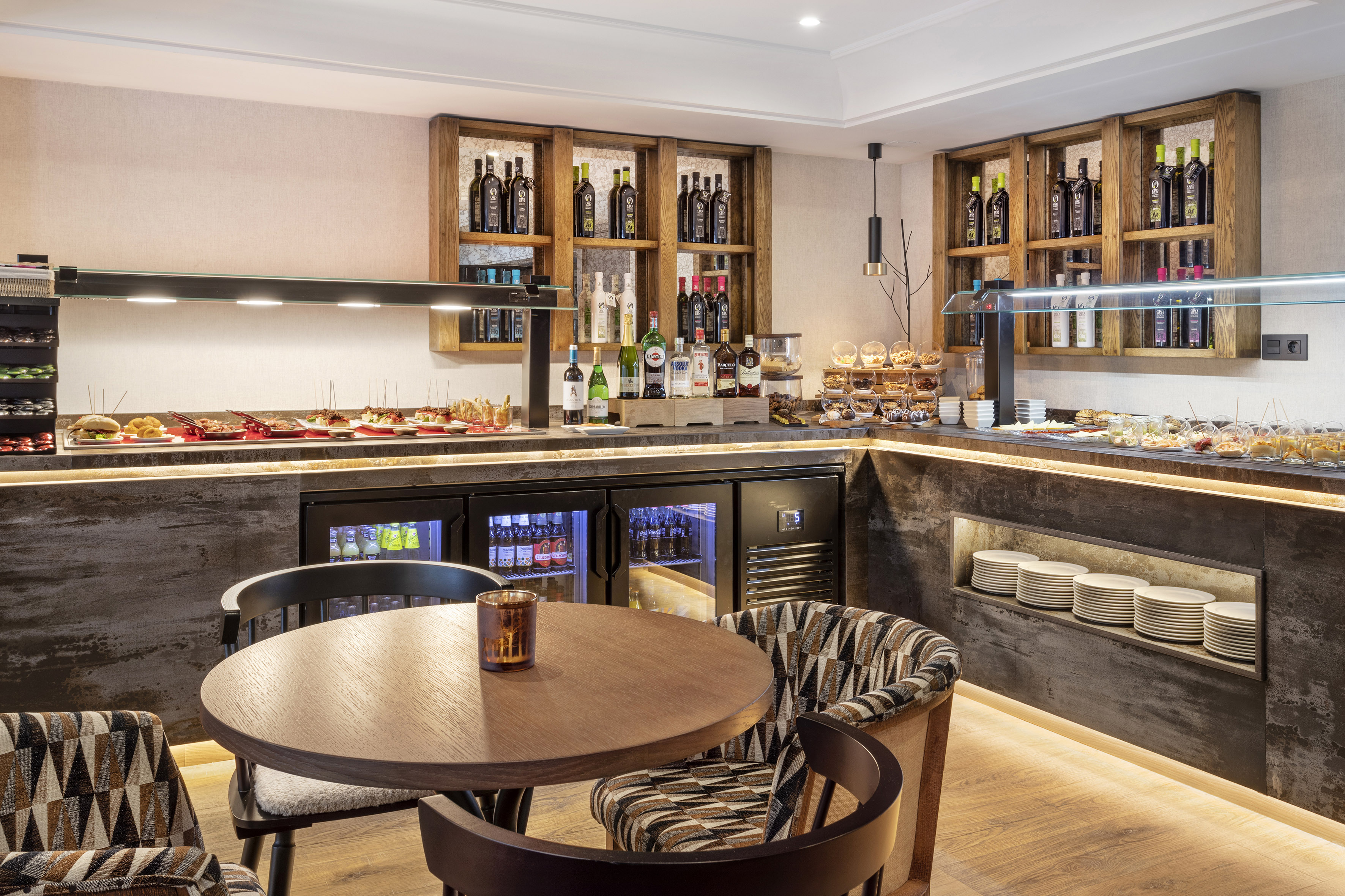 Modern hotel buffet with appetizers, bottled drinks, and comfortable seating.