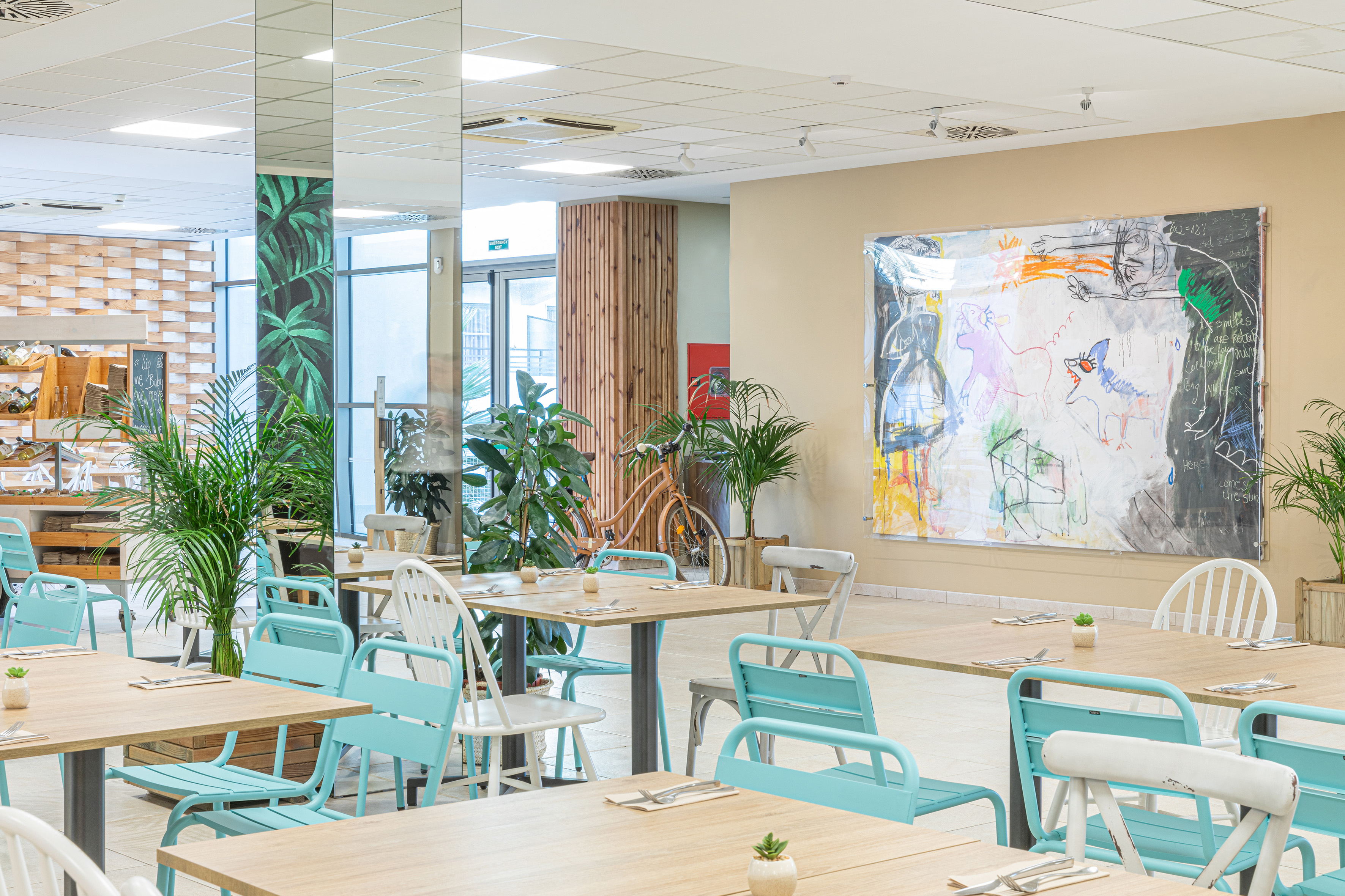 Modern dining area, turquoise chairs, wooden tables, green plants, abstract art.