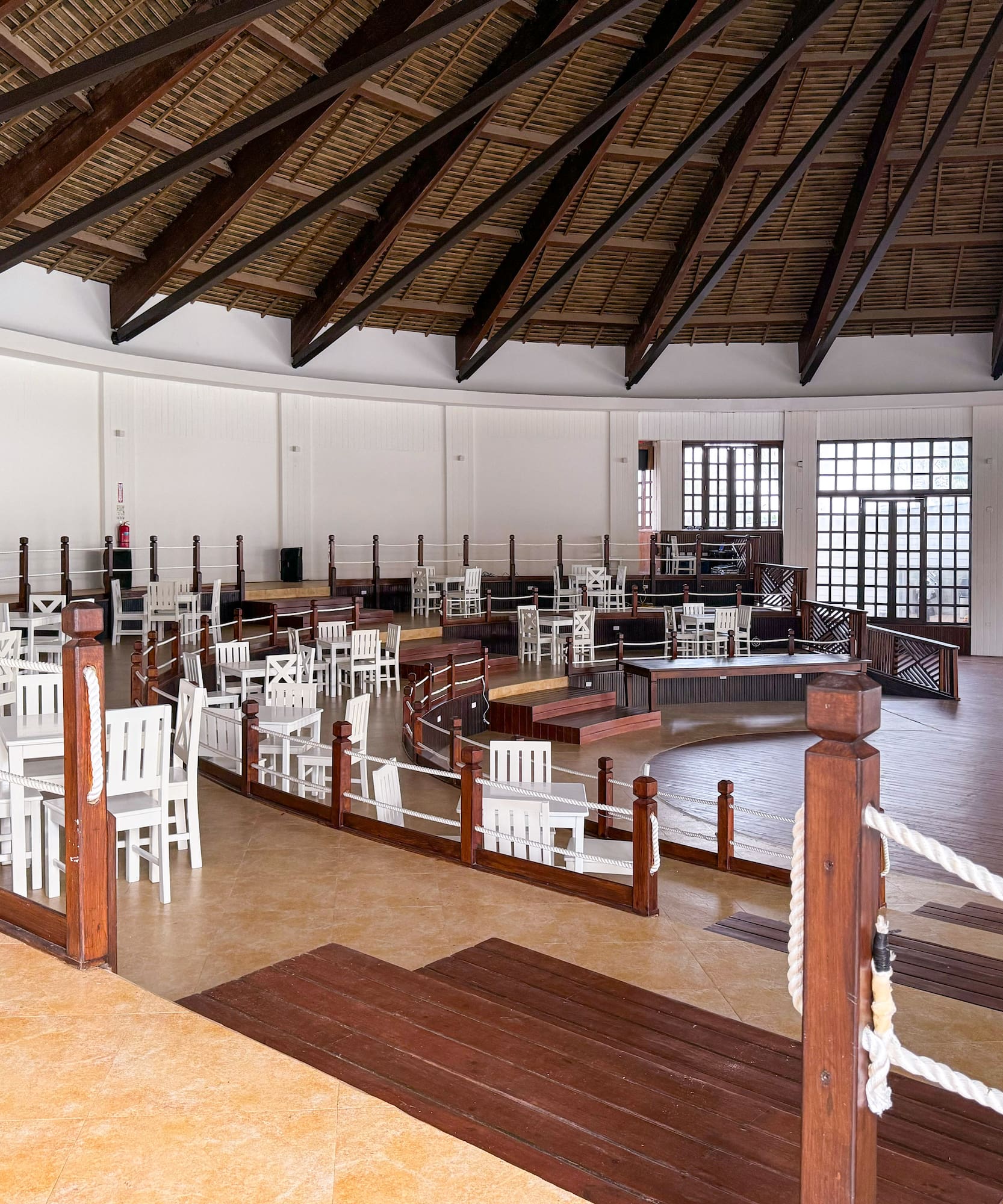 a room with white chairs and a wooden ceiling