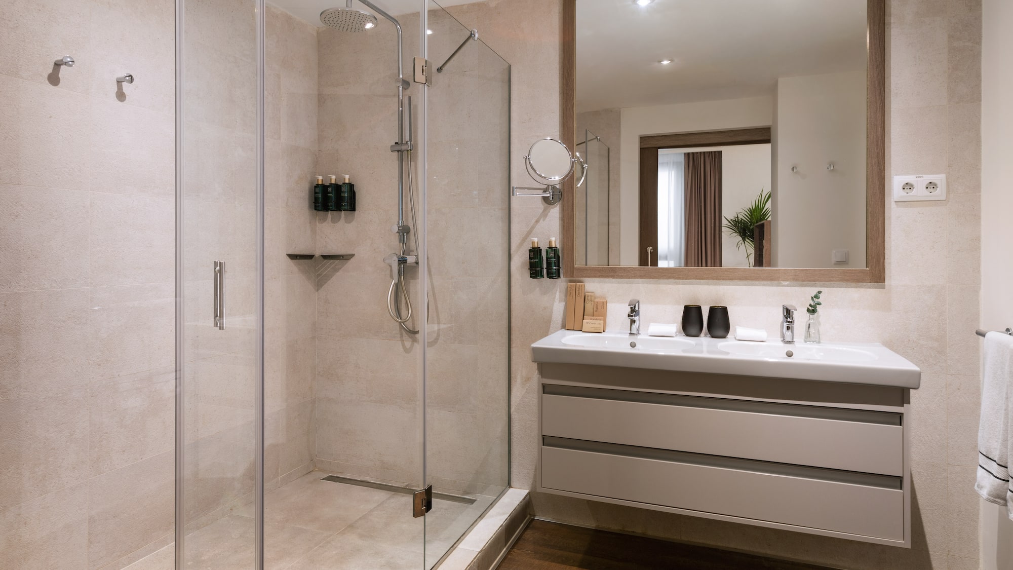 Modern hotel bathroom with glass walk-in shower and double vanity.
