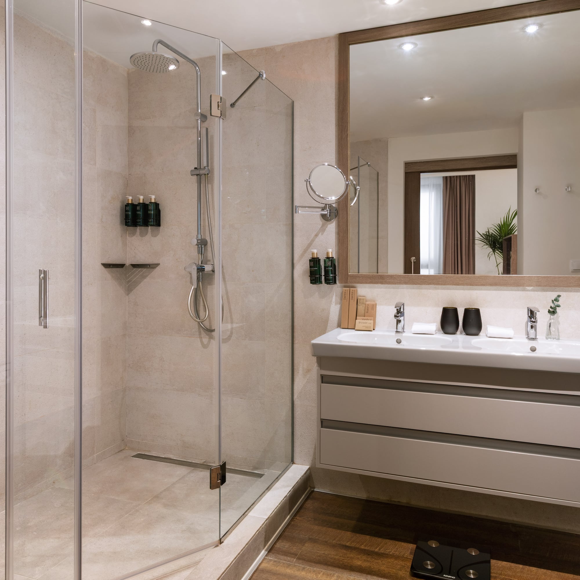 Modern hotel bathroom with glass walk-in shower and double vanity.