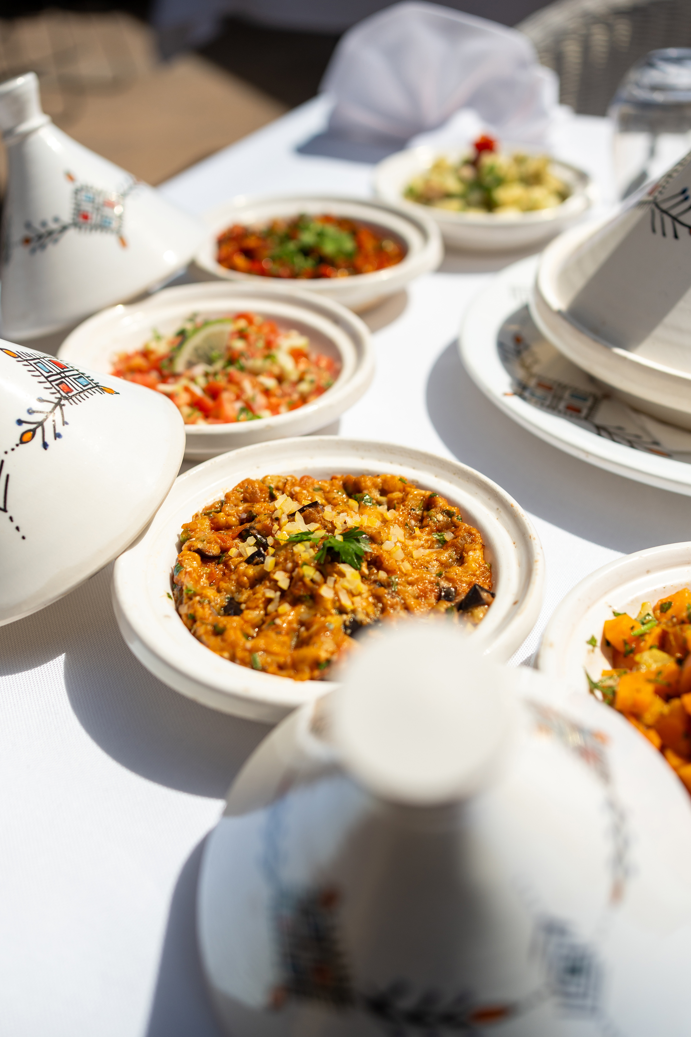 Colorful Moroccan appetizers and dips in traditional tagine dishes. - Restaurant Darna, Showkochen - SOL Oasis Marrakech, Marrakesch