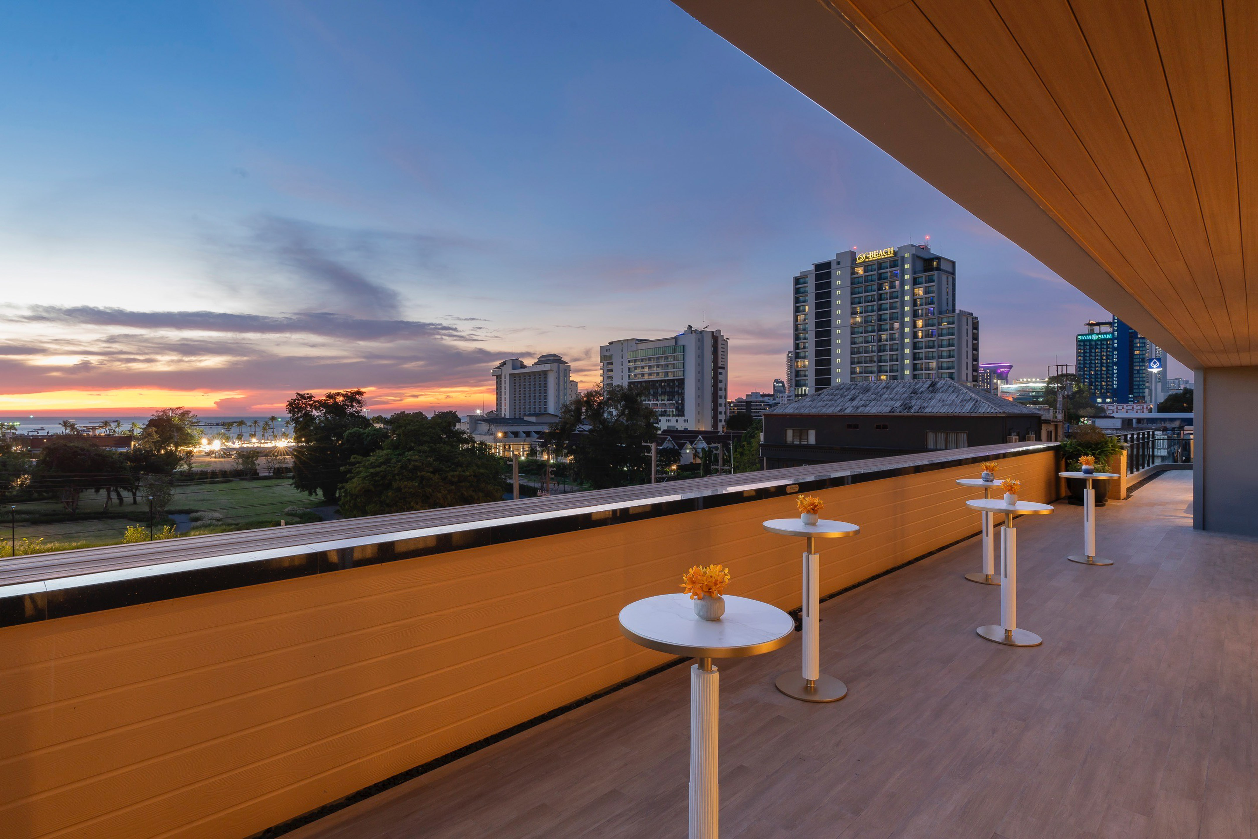 Hotel rooftop terrace at sunset with city skyline and white lounge tables. - Nuaan - Meliá Pattaya Hotel, Pattaya