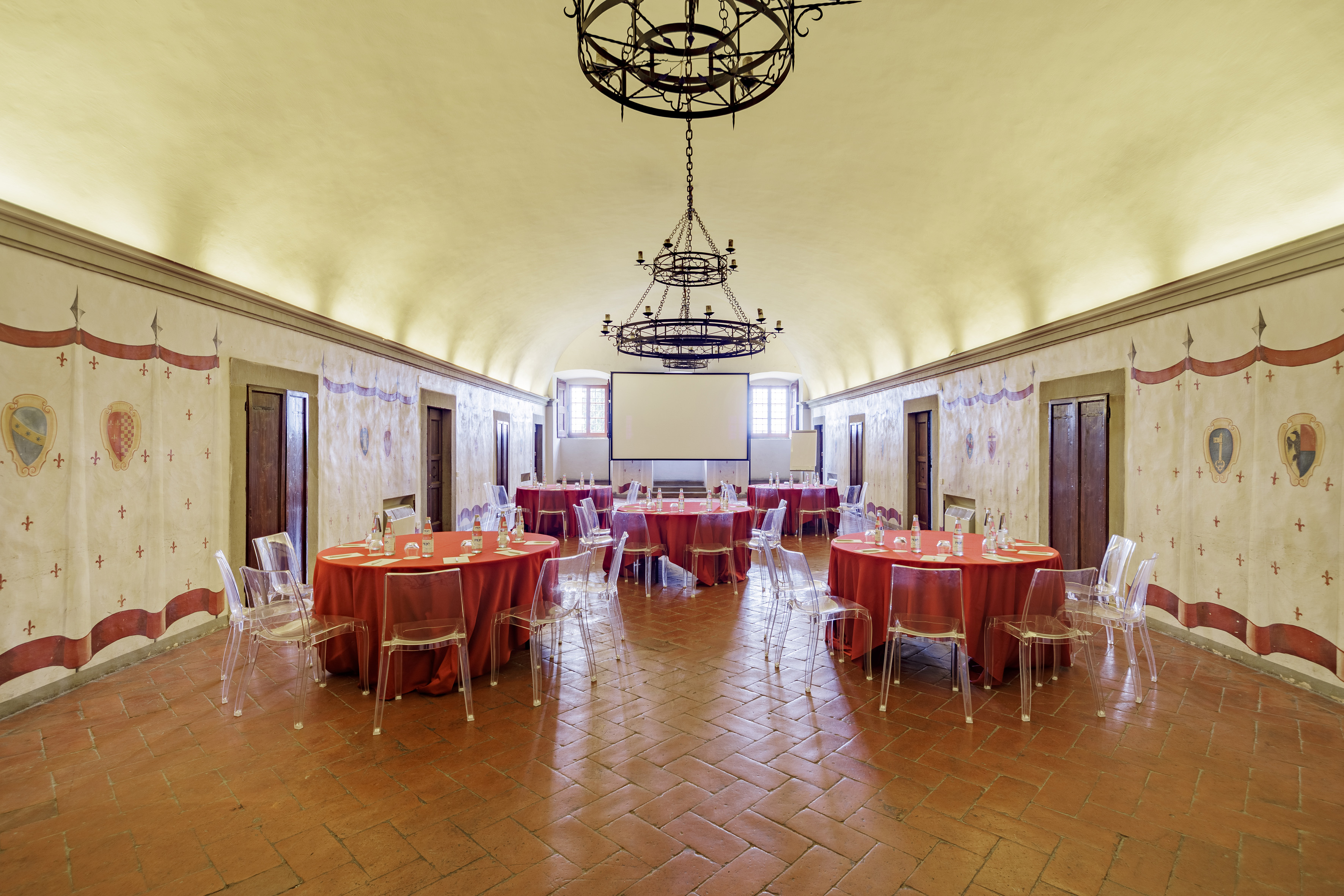 Historic event space with red tables, modern chairs, projector, and ornate walls.