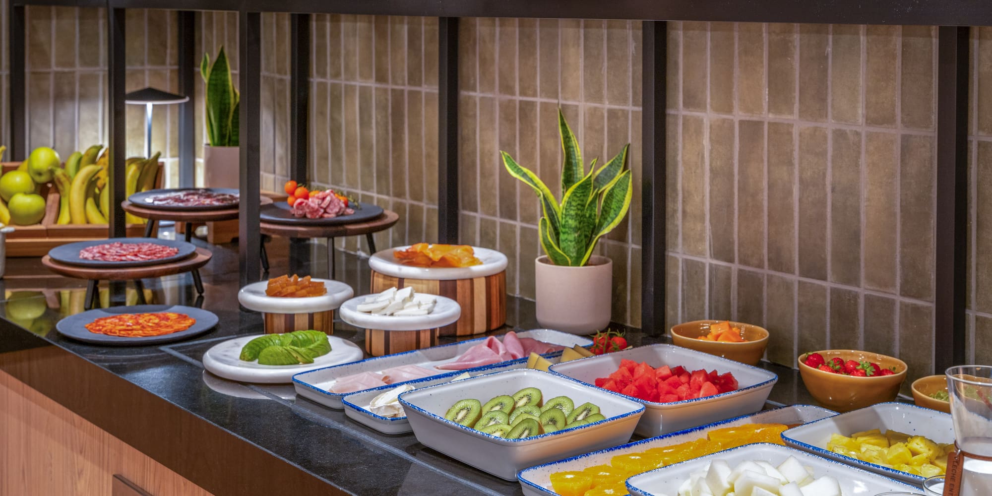 Variado desayuno buffet con frutas, embutidos y quesos frescos.
