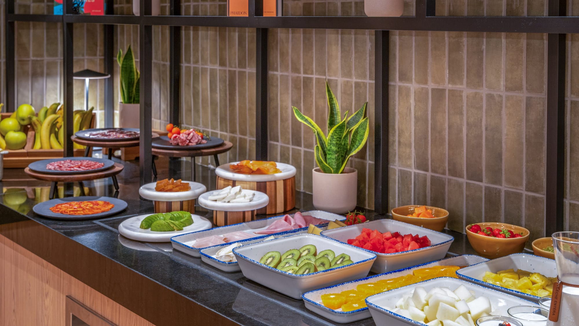Variado desayuno buffet con frutas, embutidos y quesos frescos.