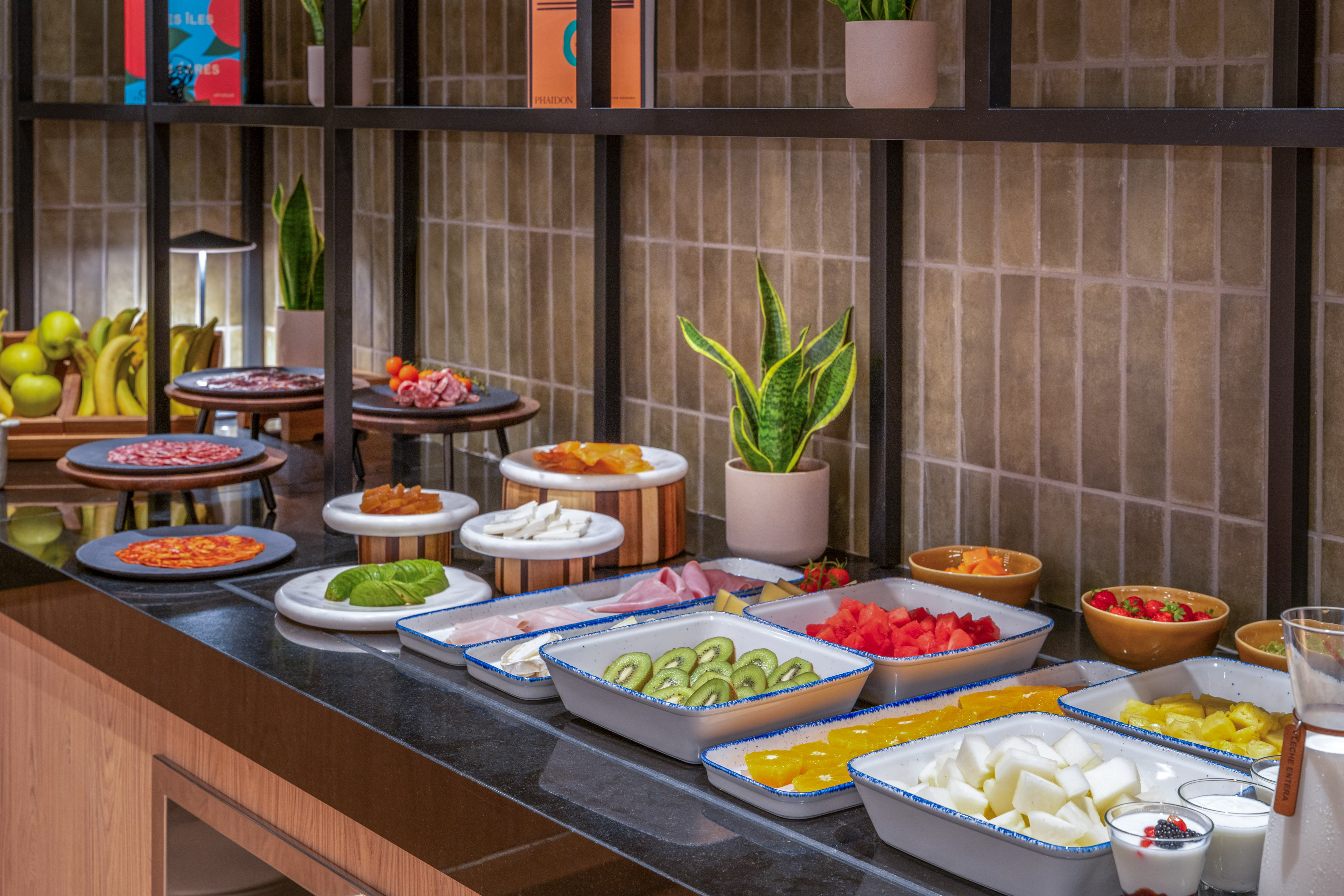 Variado desayuno buffet con frutas, embutidos y quesos frescos.