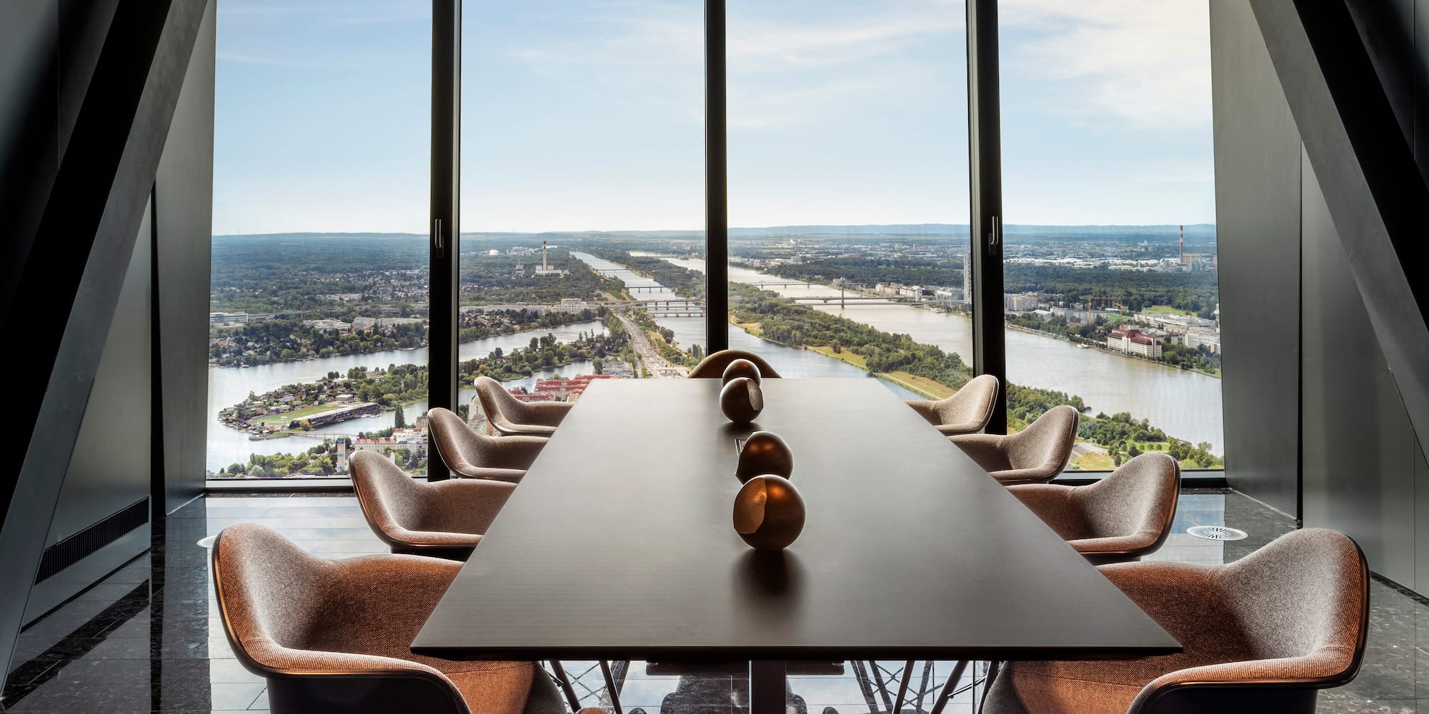 a room with a table and chairs and a view of a river and city