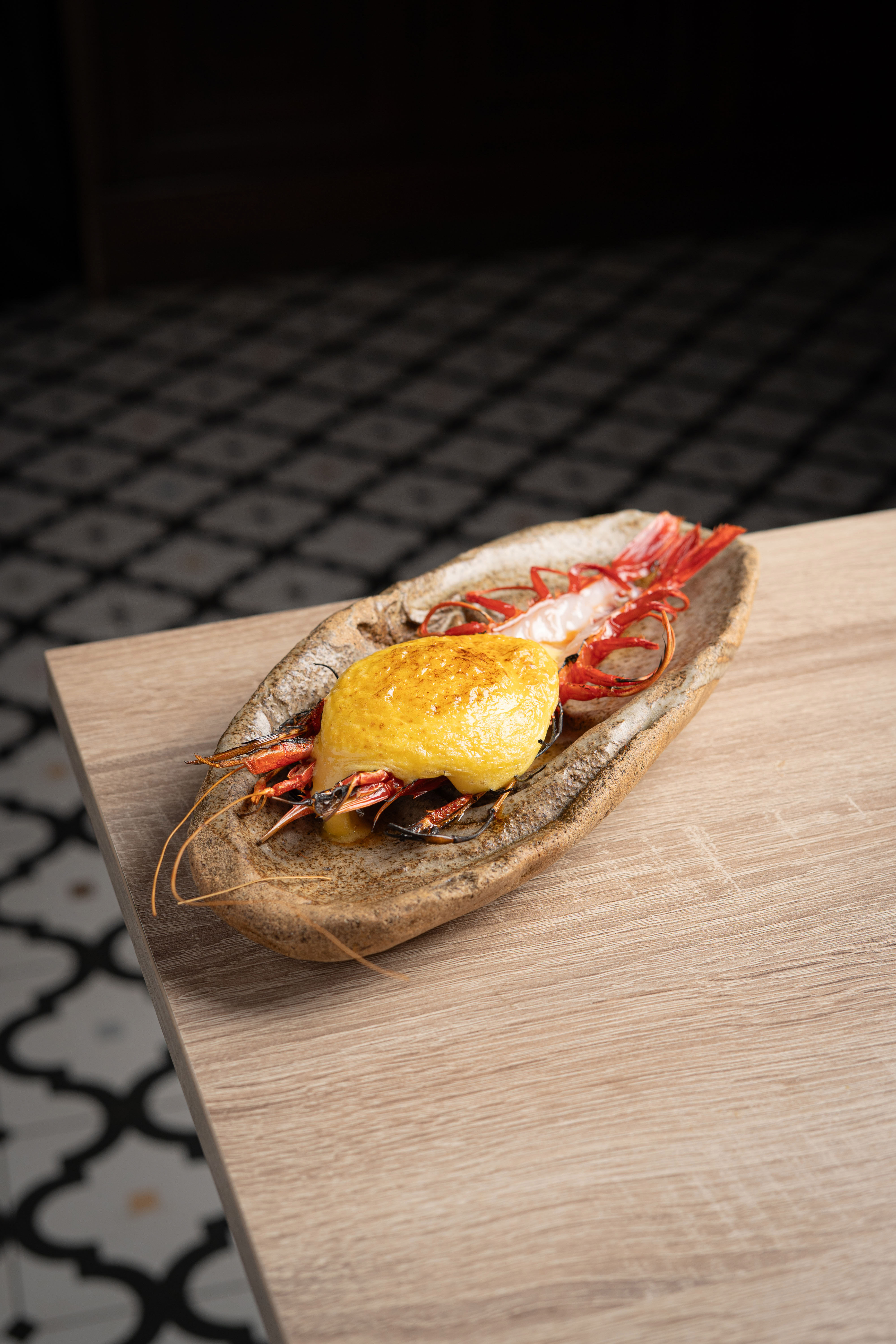Cooked red prawns with golden gratin in an artisanal ceramic dish.