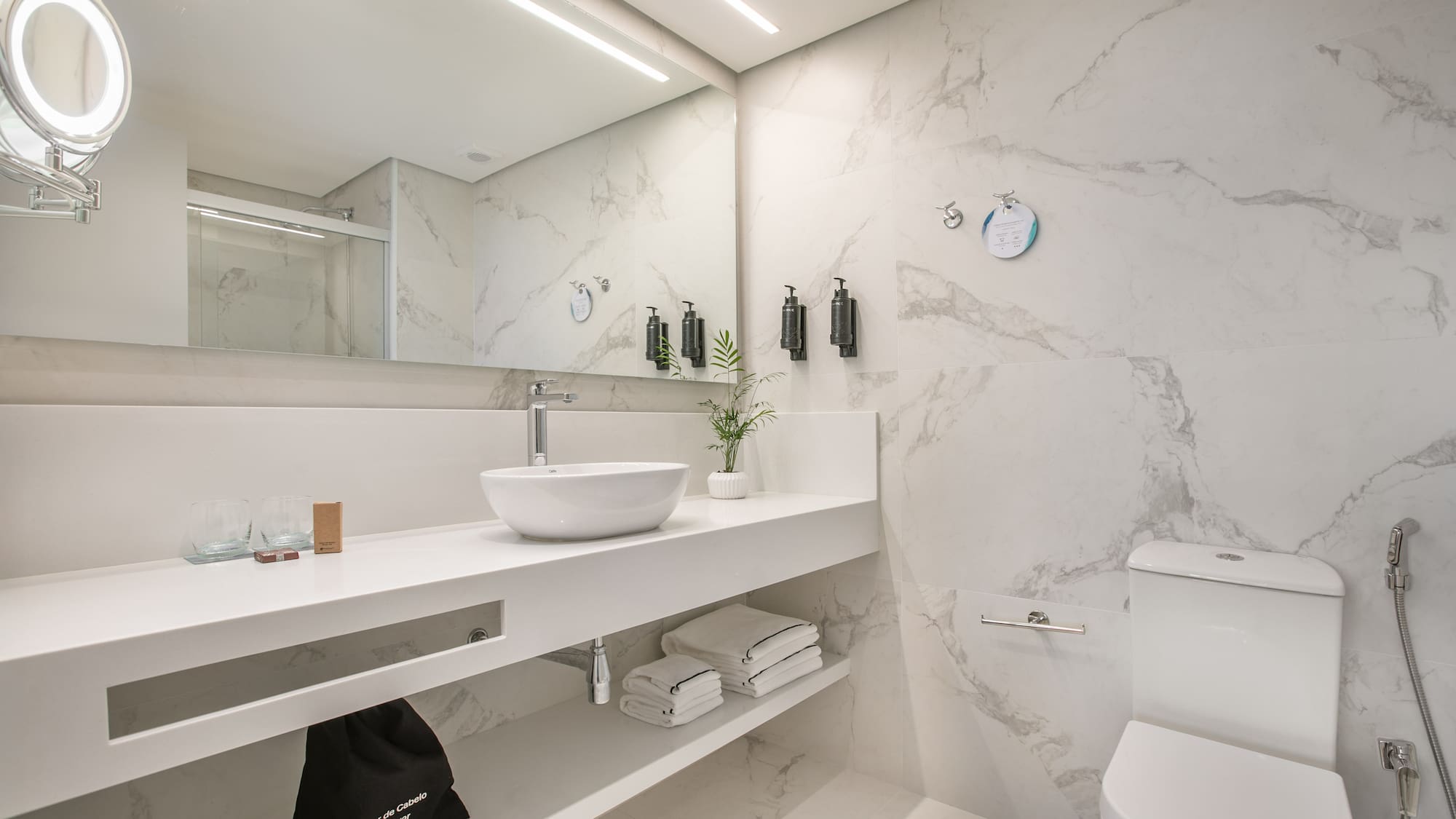 Clean white marble bathroom with modern floating vanity, vessel sink, and toilet.