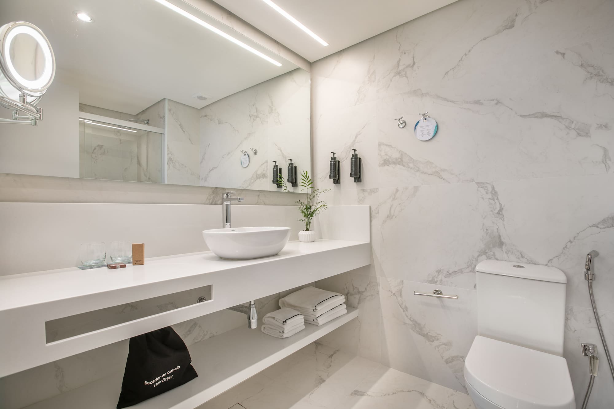 Clean white marble bathroom with modern floating vanity, vessel sink, and toilet.
