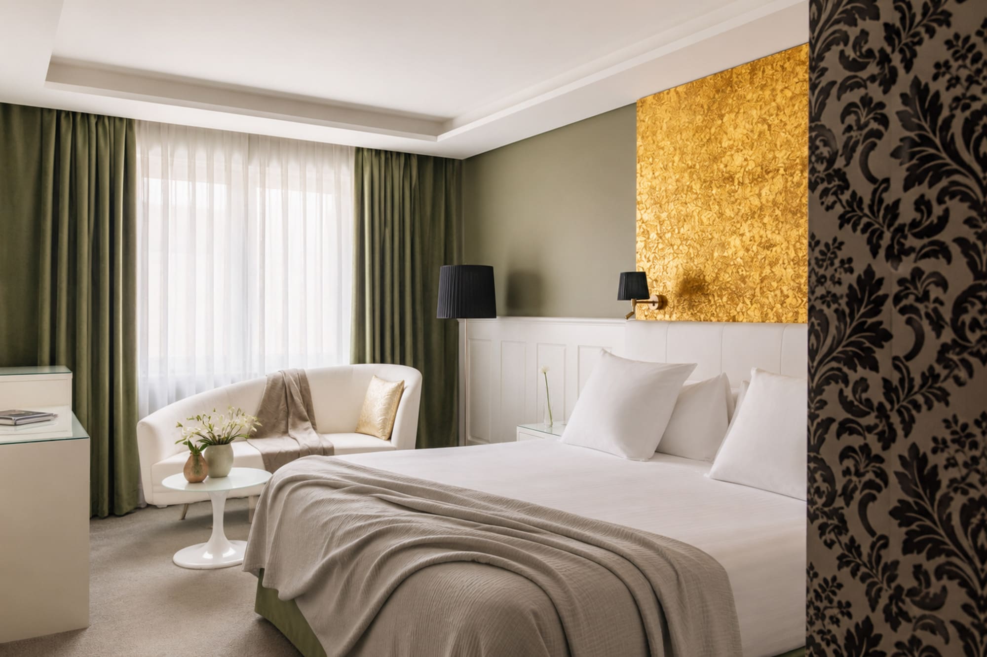 Luxury hotel room with gold accent wall, white bed, olive green curtains.