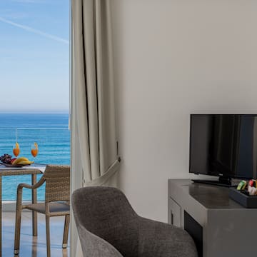 a room with a television and a table and chairs by the ocean