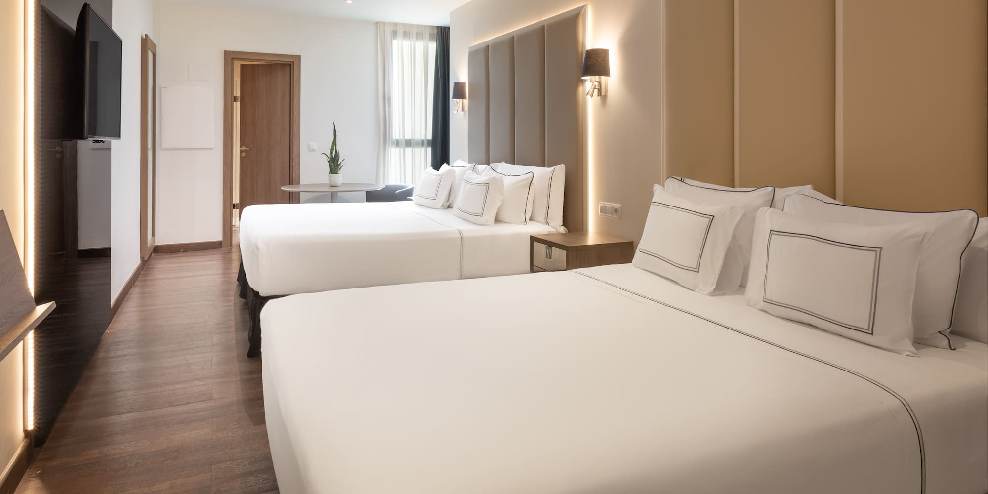 Modern hotel room with two beds, crisp white linen, and wood floor.