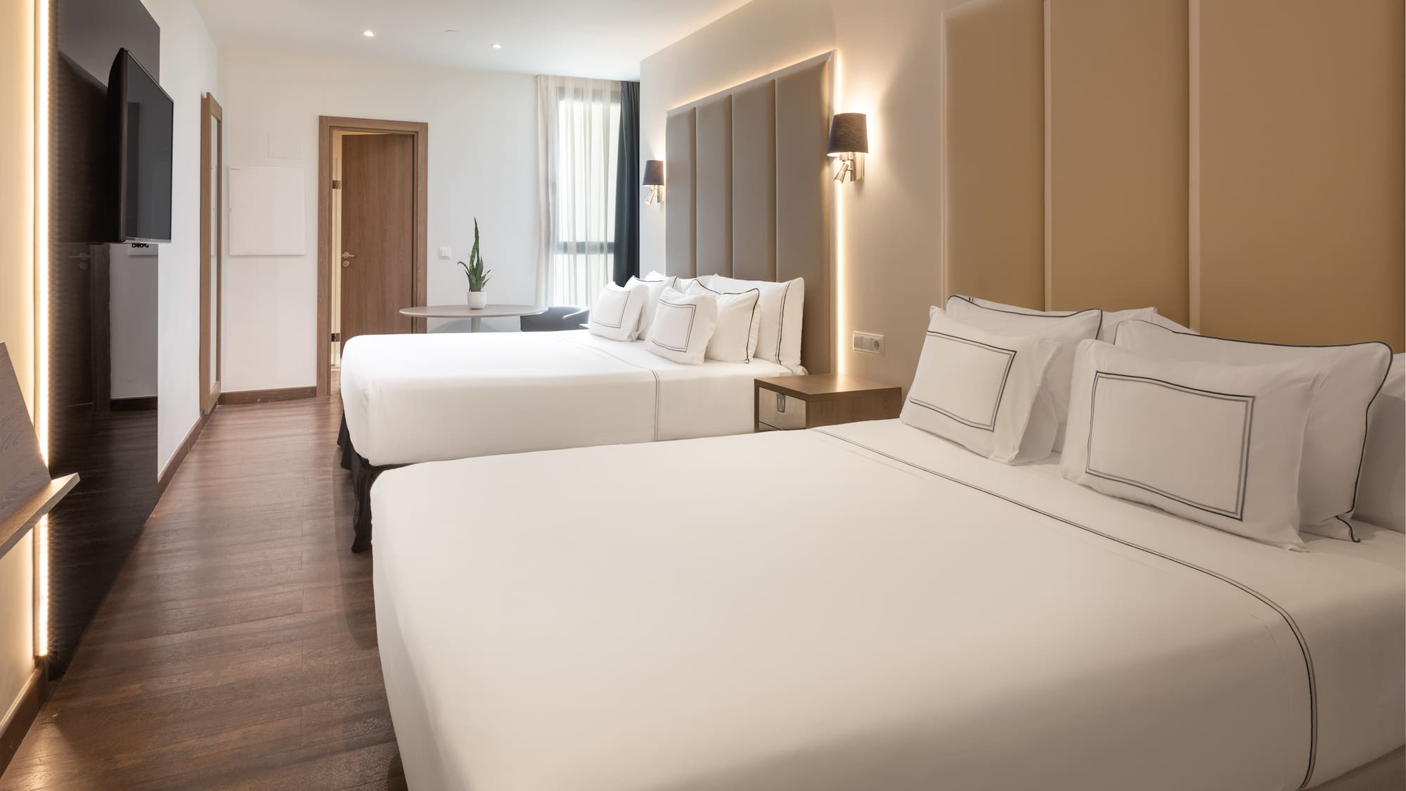 Modern hotel room with two beds, crisp white linen, and wood floor.