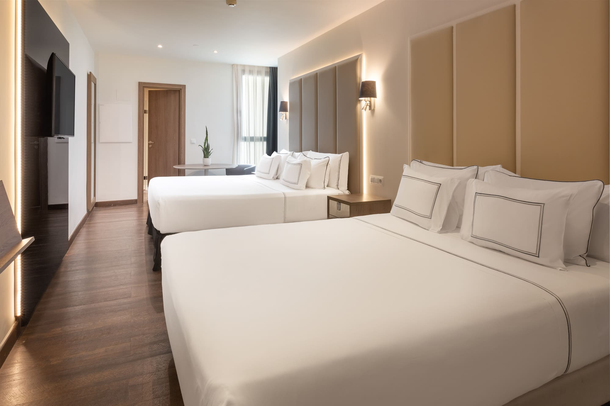 Modern hotel room with two beds, crisp white linen, and wood floor.