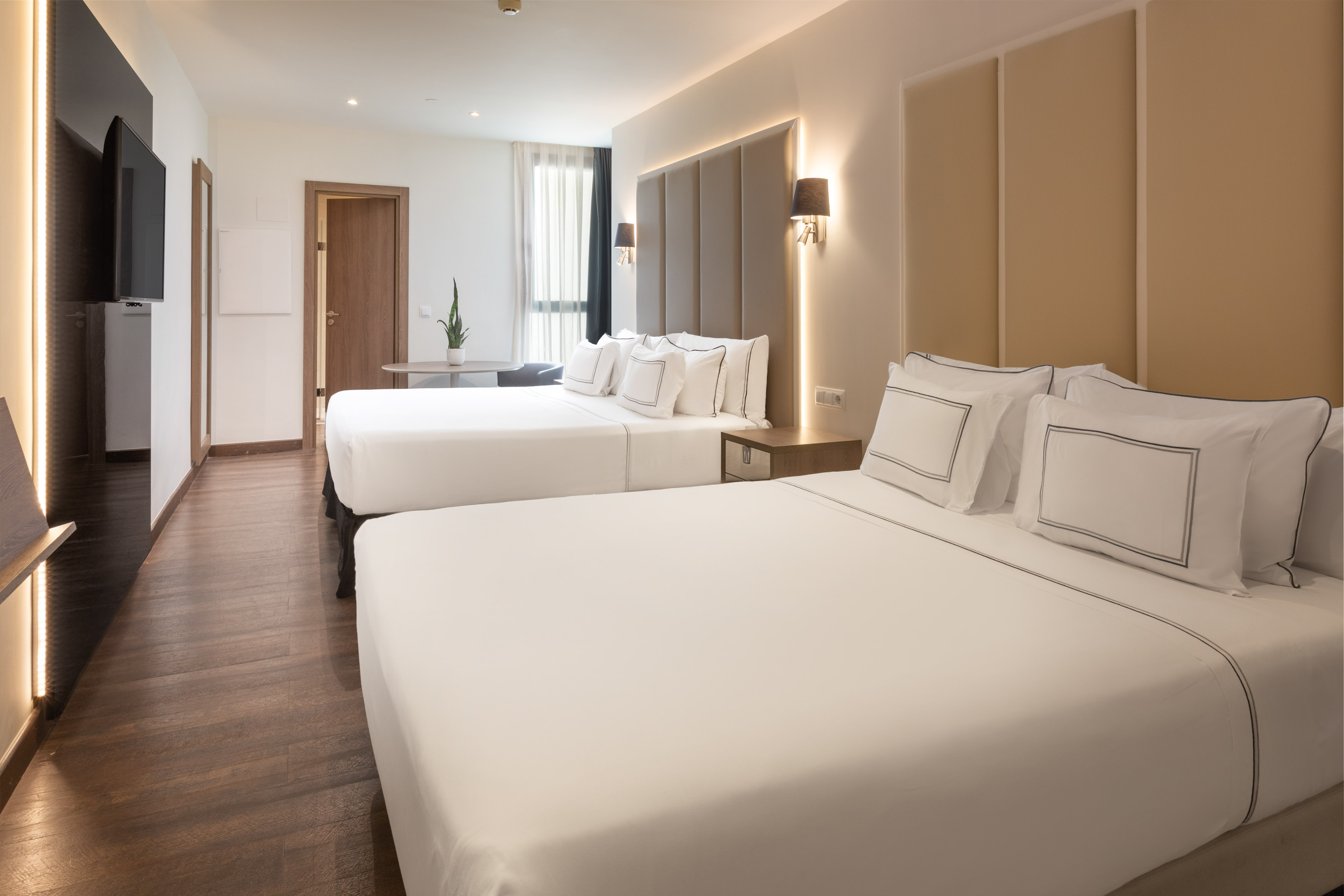Modern hotel room with two beds, crisp white linen, and wood floor.