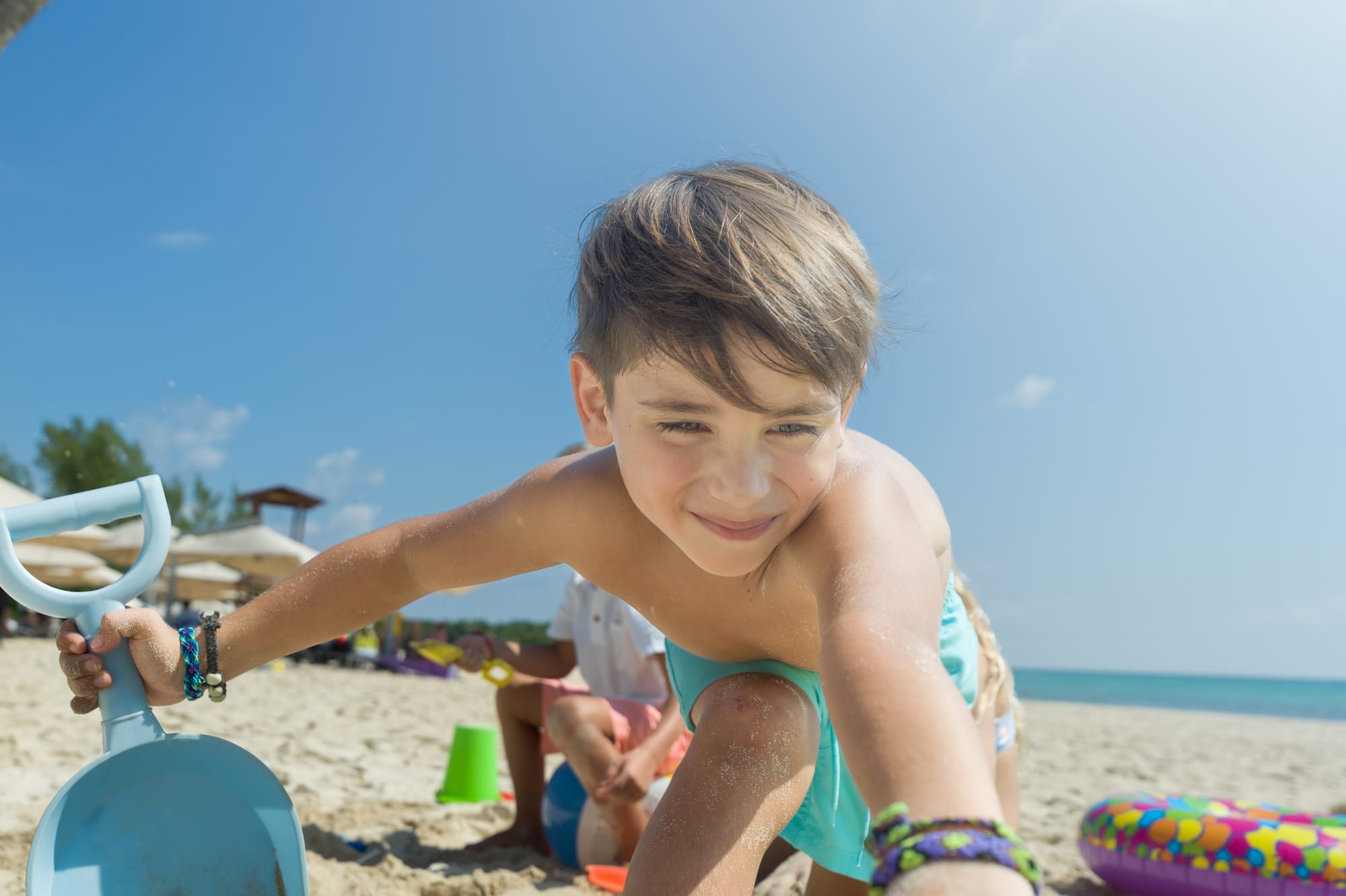 a boy playing with a shovel on a beach