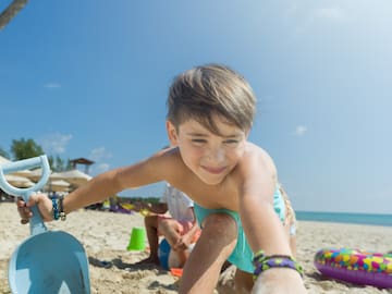 a boy playing with a shovel on a beach