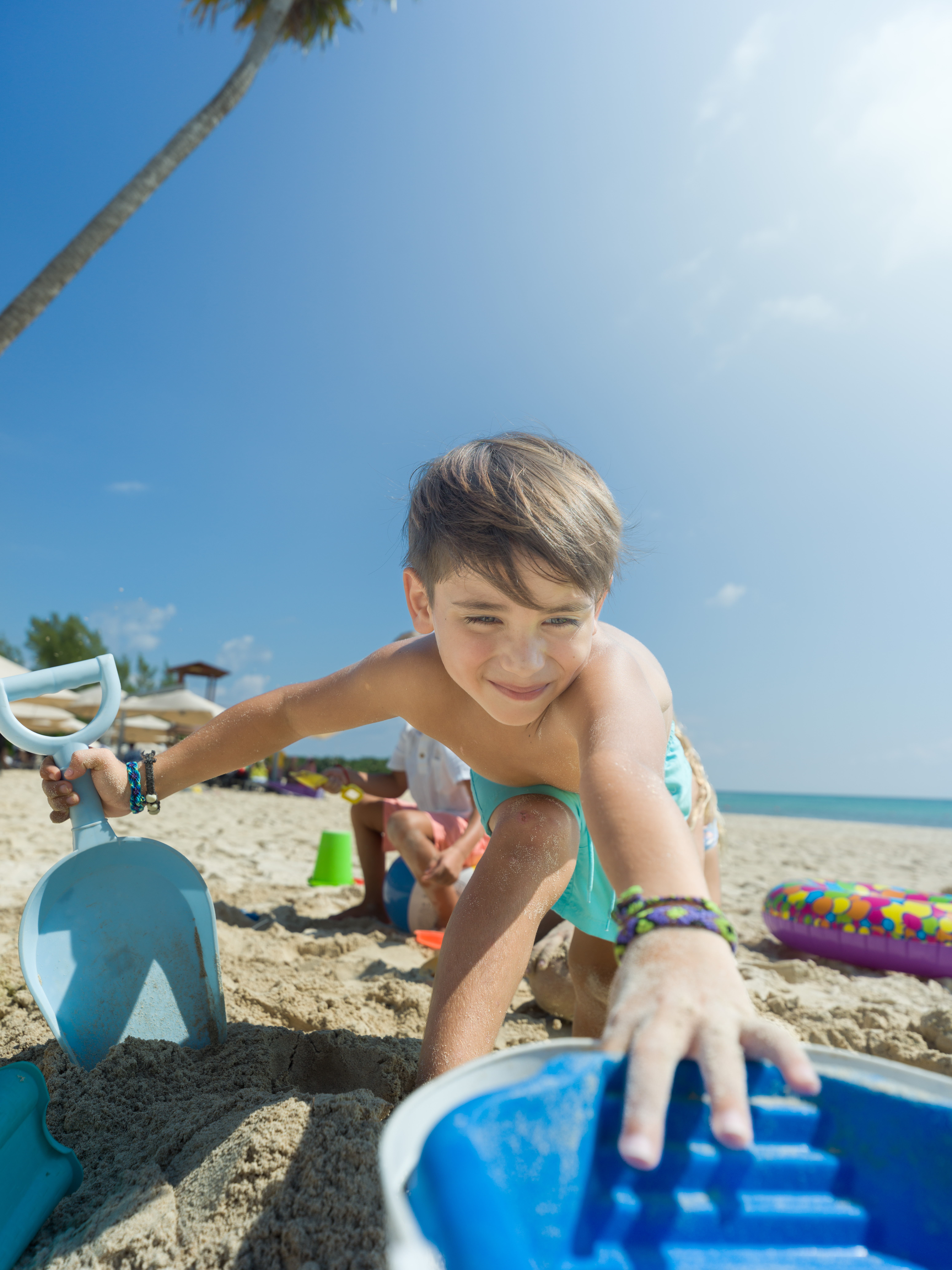 a boy playing with a shovel on a beach
