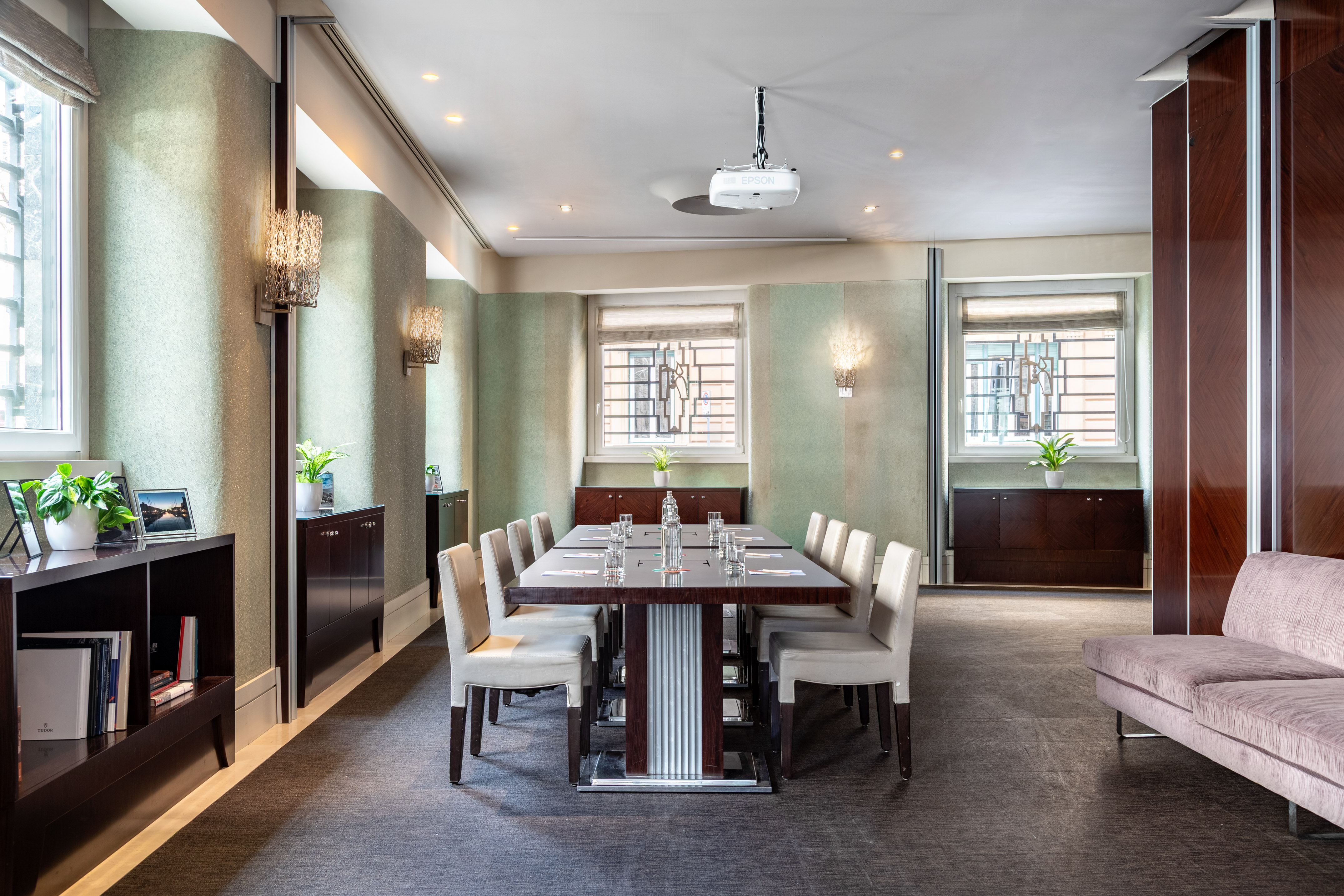 Elegant corporate meeting room with large table, chairs, and ceiling projector.