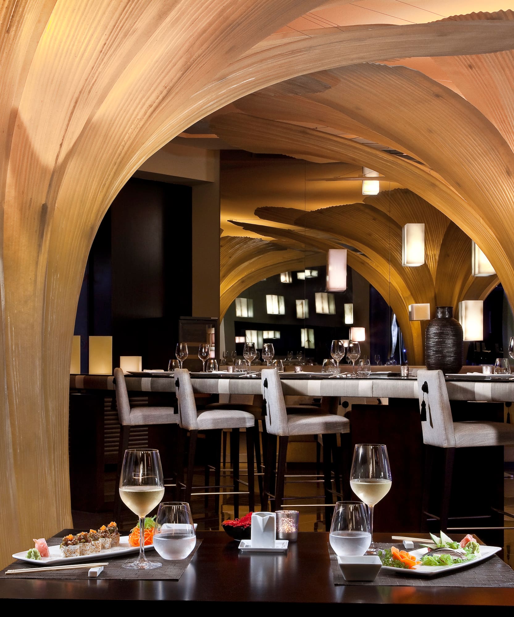 Modern restaurant interior with unique wooden archways, sushi, and bar area.