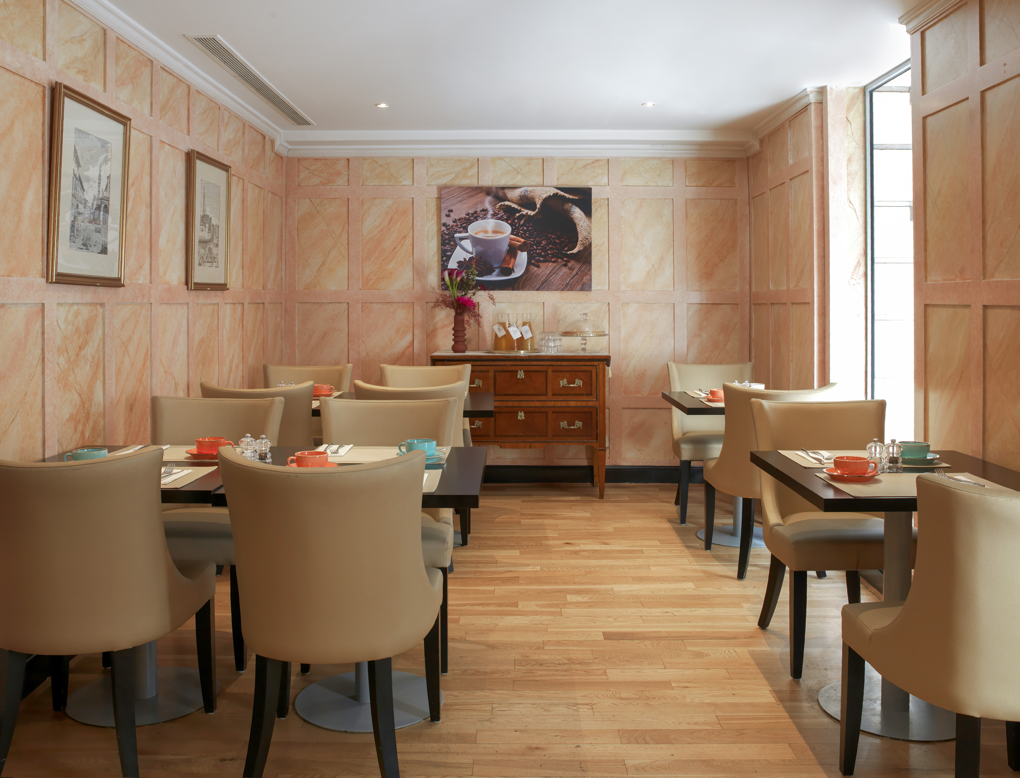 Small hotel breakfast room with set tables, tan chairs, wood floor, and coffee art.
