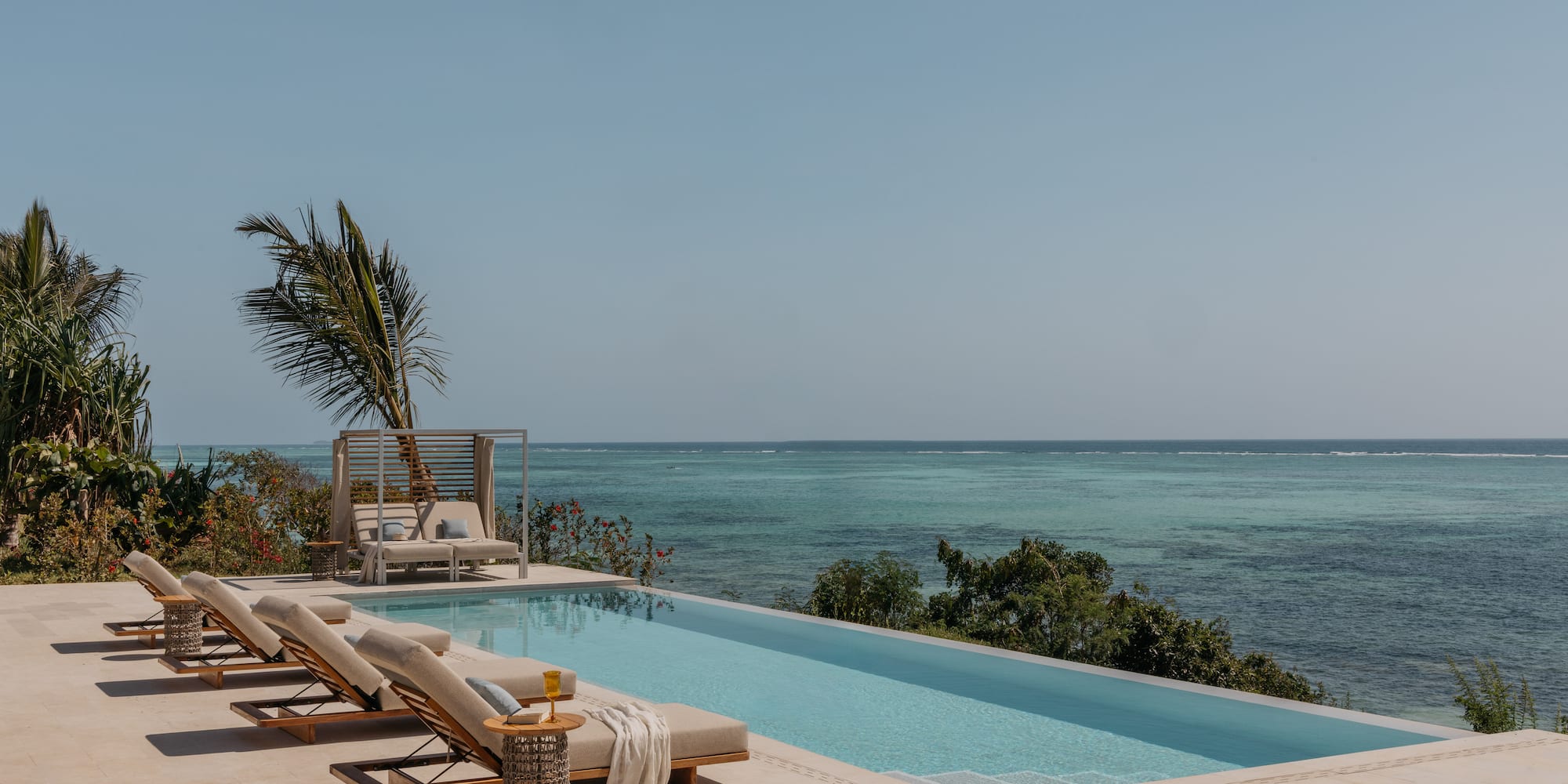 a pool with lounge chairs and a palm tree overlooking the ocean